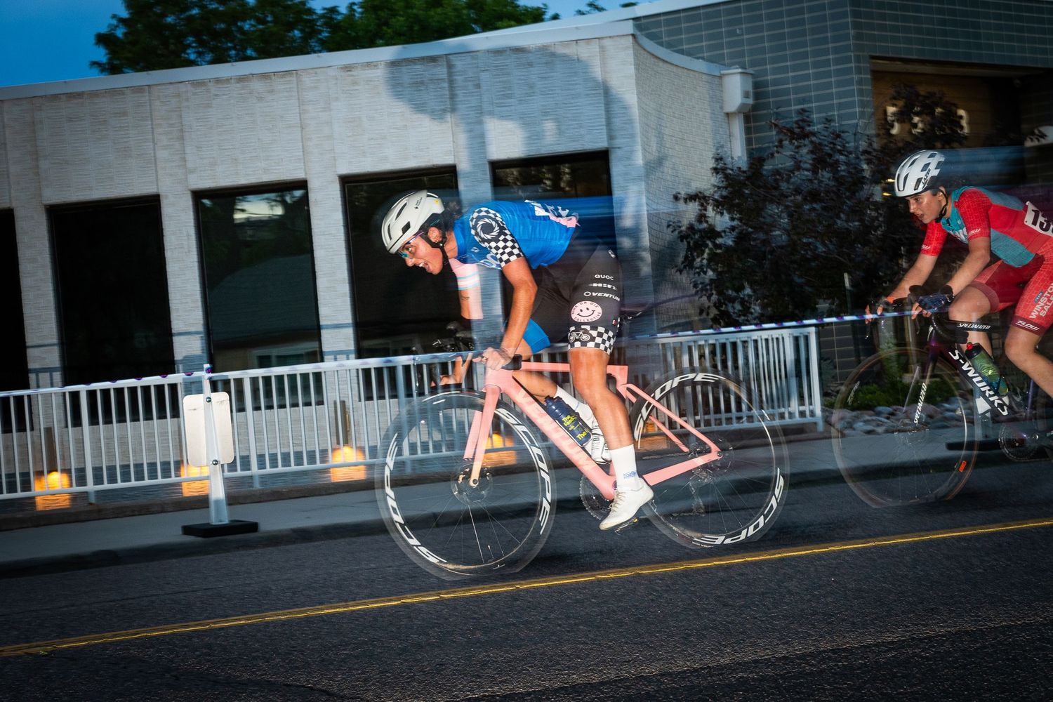 Female cyclist racing at high speed during the Littleton Twilight Criterium in Colorado, captured with motion blur for a dynamic effect.