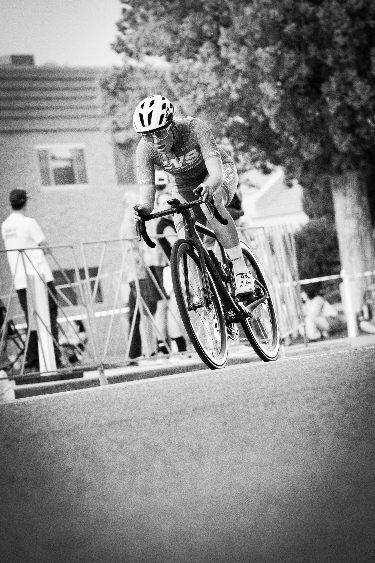 Female cyclist racing in the Littleton Twilight Criterium in Colorado, captured in black and white.