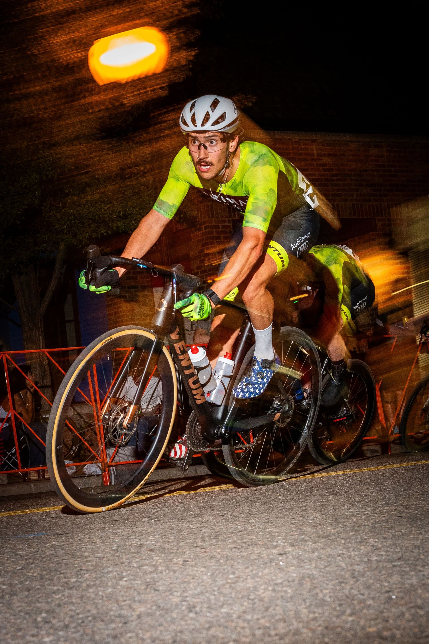 Male cyclist racing at high speed during the Littleton Twilight Criterium in Colorado, captured with motion blur for a dynamic effect.
