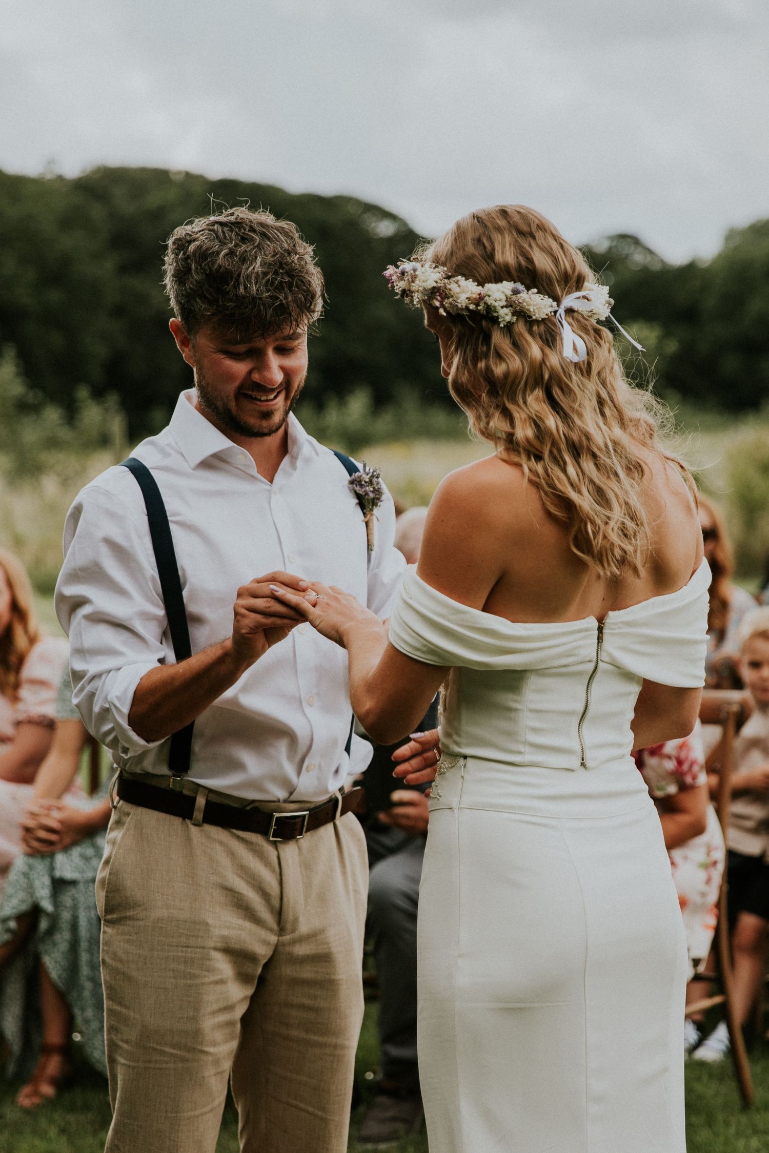 Outdoor wedding dance with couple in white and khaki attire.