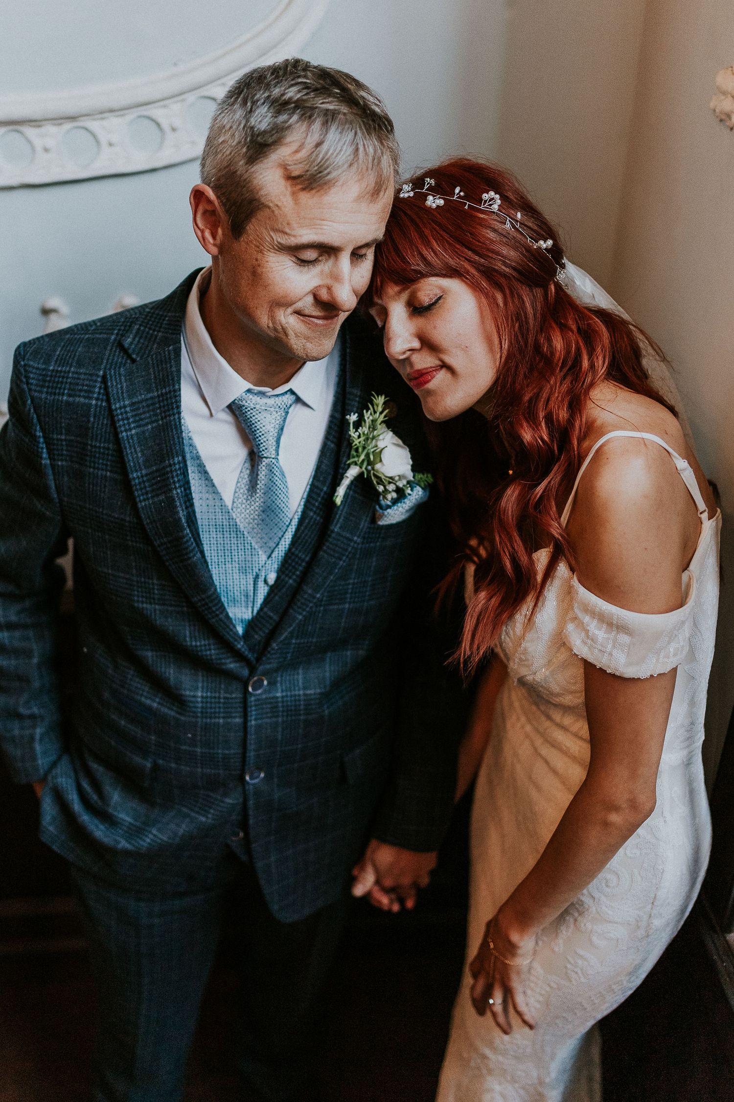 Intimate portrait of newlyweds sharing tender moment in soft window light.
