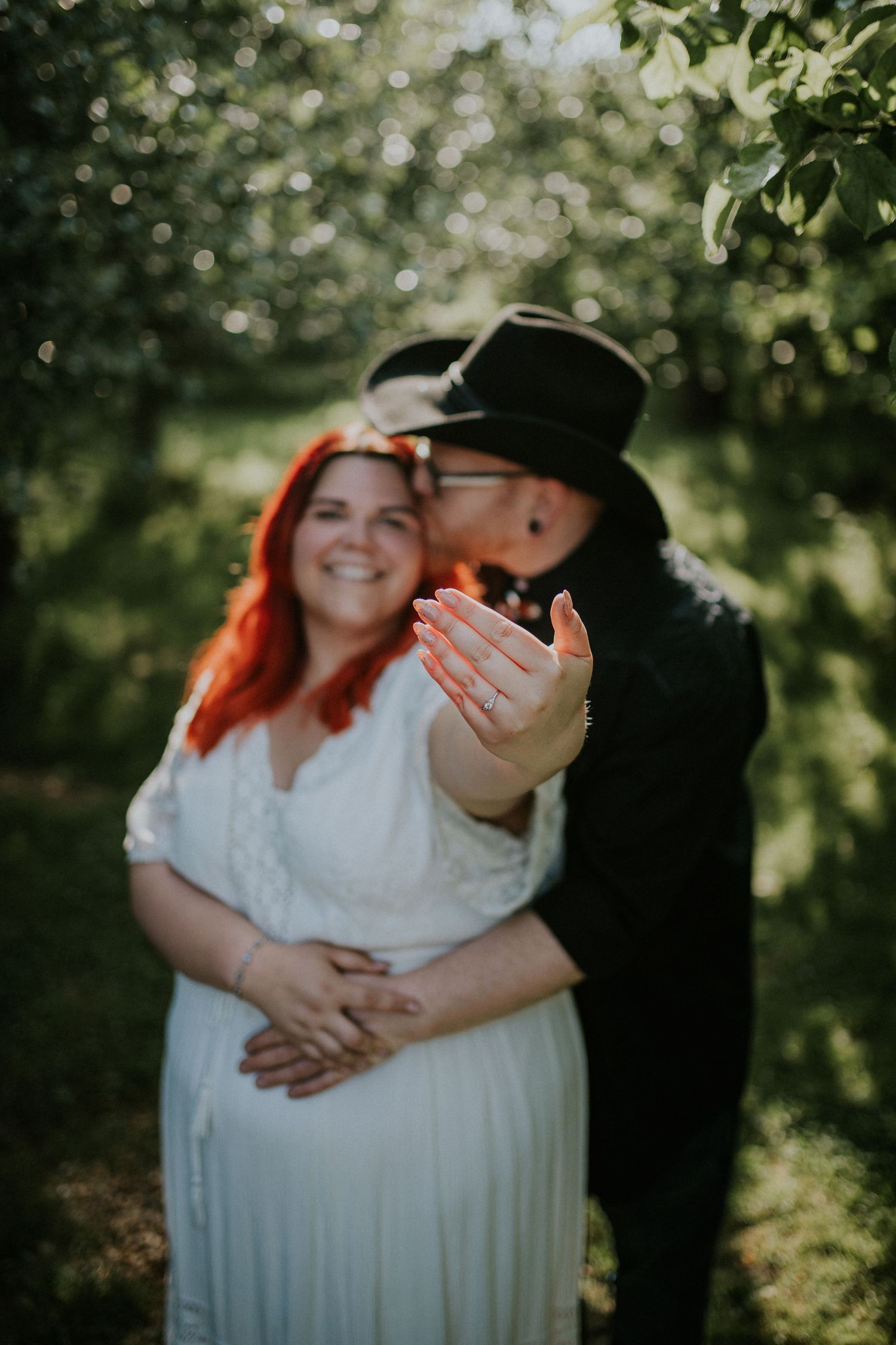 Dancing newlyweds share happy moment in dappled garden light.