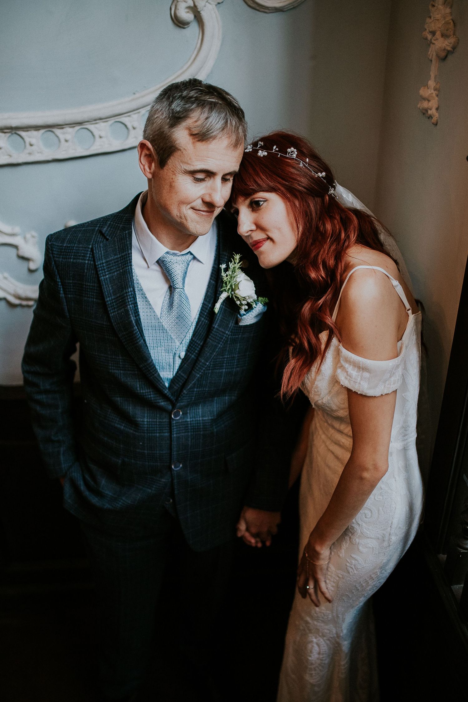 Tender moment between newlyweds in a vintage-inspired indoor setting.