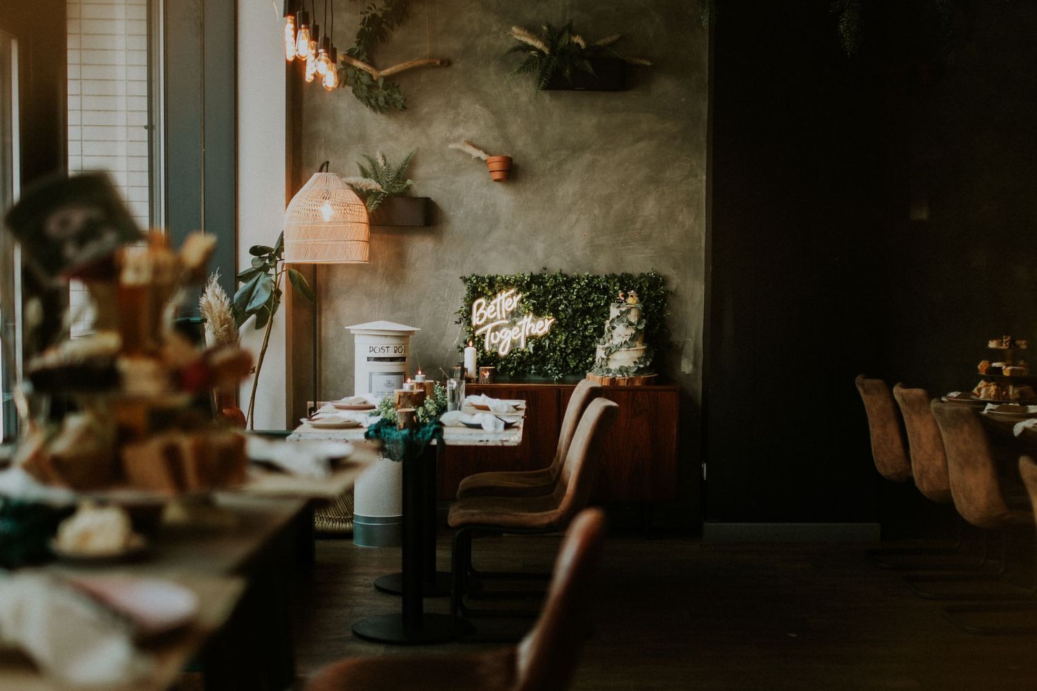 Moody interior shot of a rustic dining room with pendant lighting and decorative wall art.