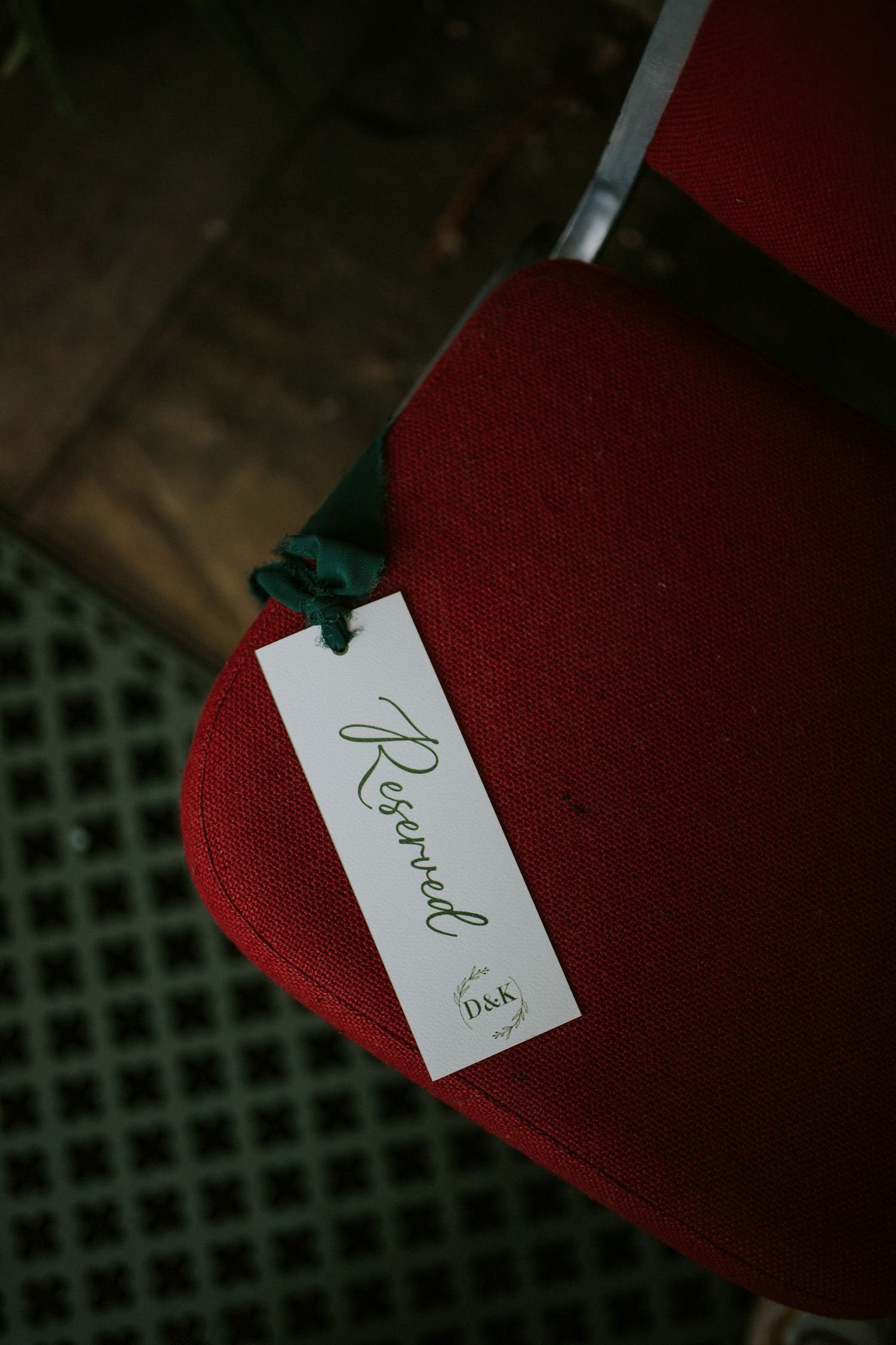 A red chair with a white reserved tag attached photographed in moody lighting.