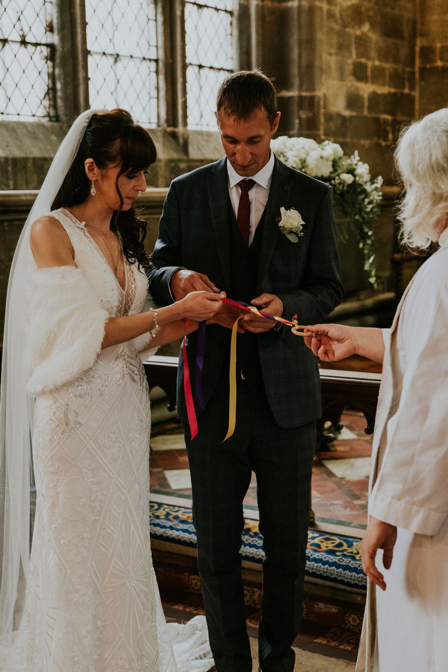 Wedding ceremony in progress inside historic stone church with stained glass windows.