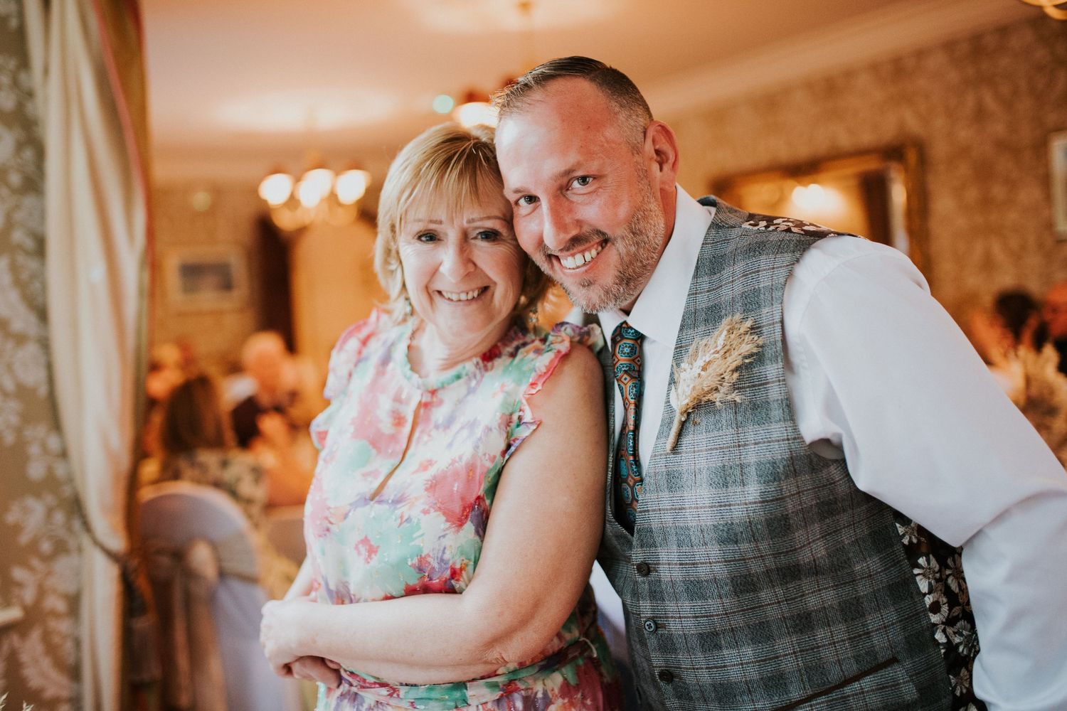 Romantic wedding moments captured in warm lighting against floral wallpaper.