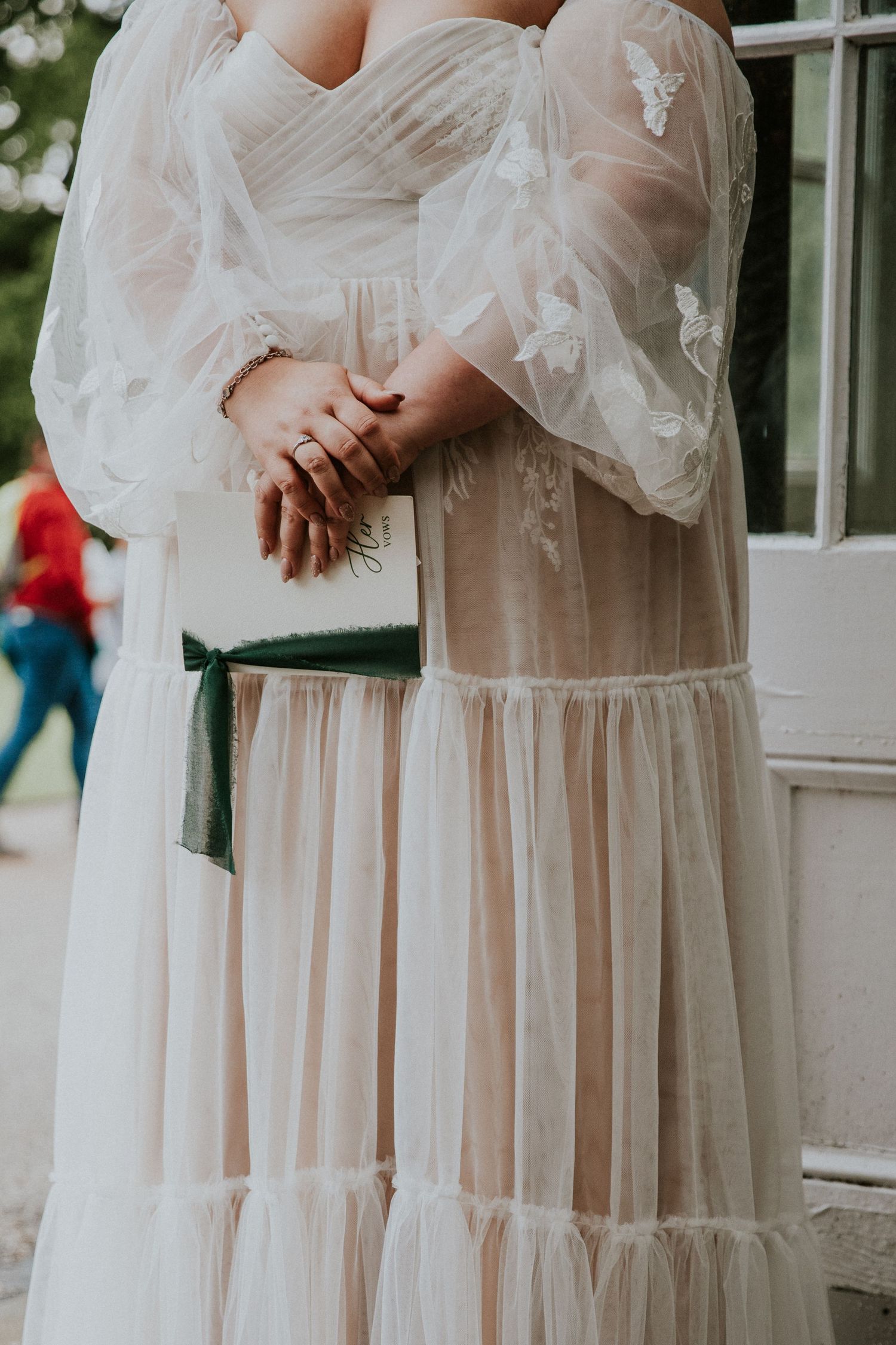 Close-up detail of a bride's hands and flowing white wedding dress.
