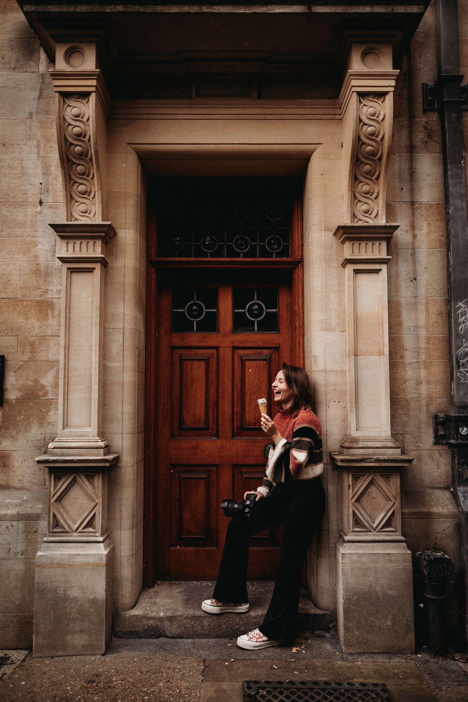 Person standing by ornate wooden door entrance with classical stone architecture.