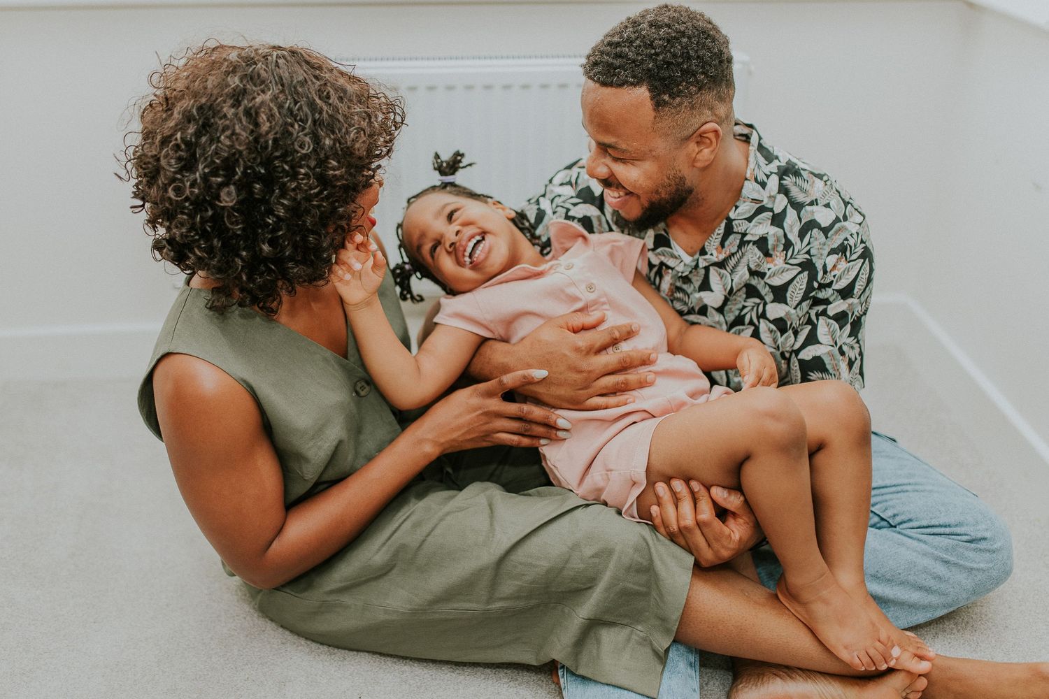 Family members lying down together sharing joyful laughter in casual attire.