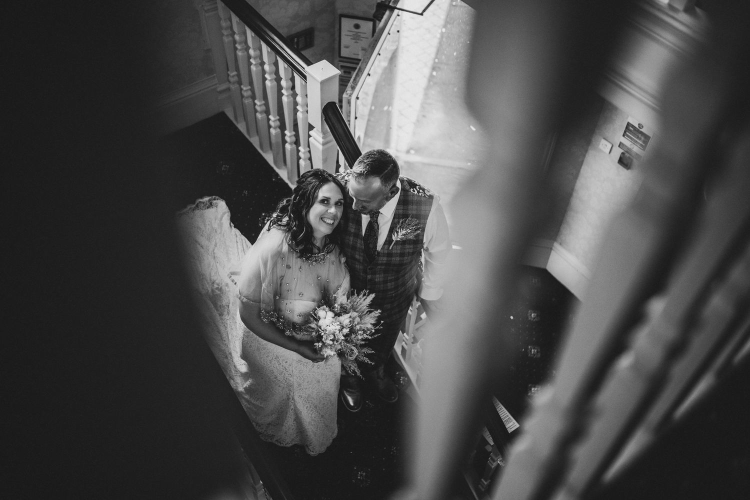 Black and white wedding photo captured through stair railings.
