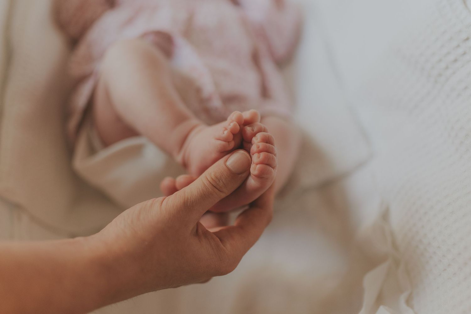 Close-up details of gentle hands against soft white fabric.