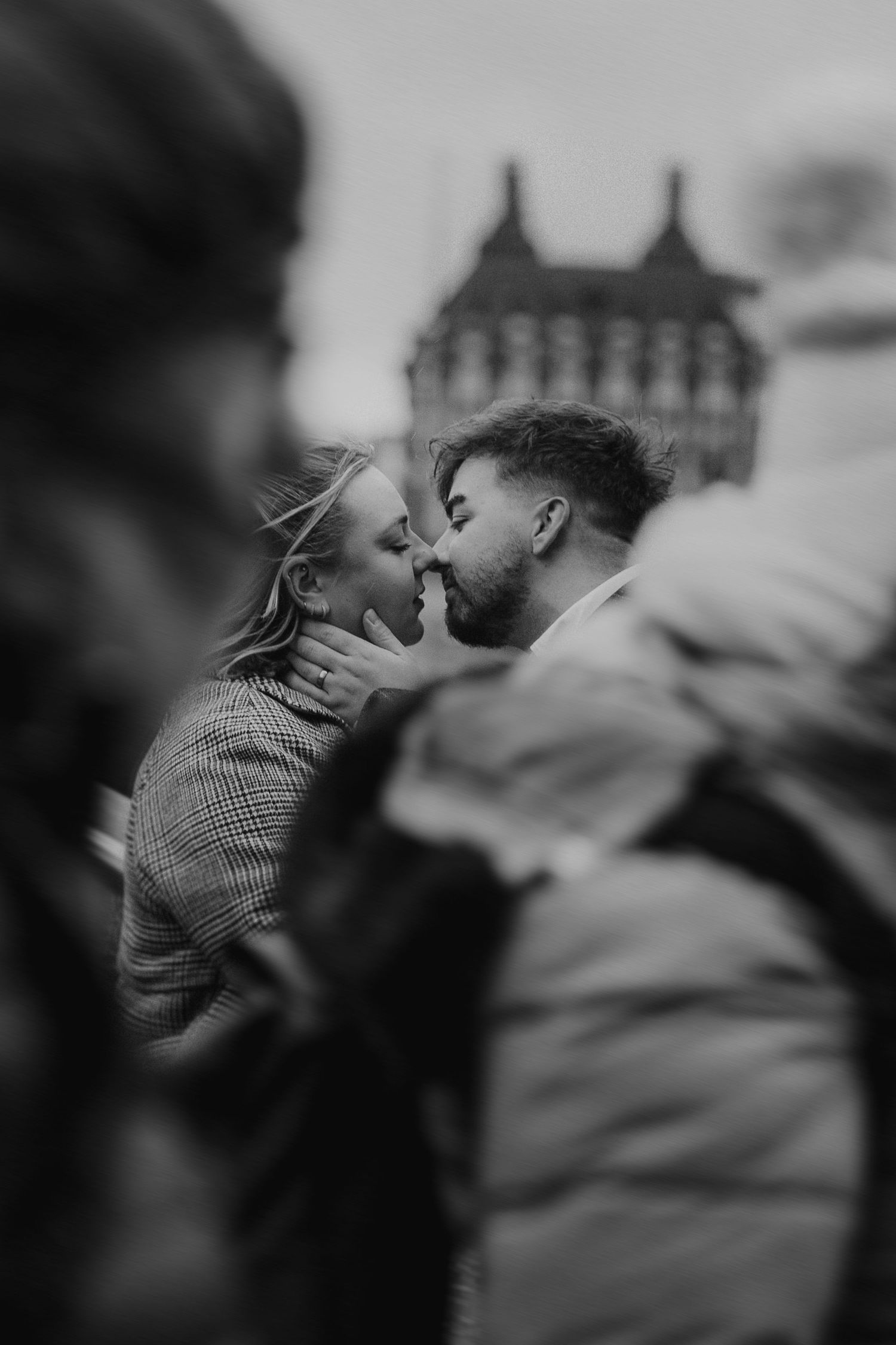An intimate moment captured between a couple in black and white with historic architecture in the background.