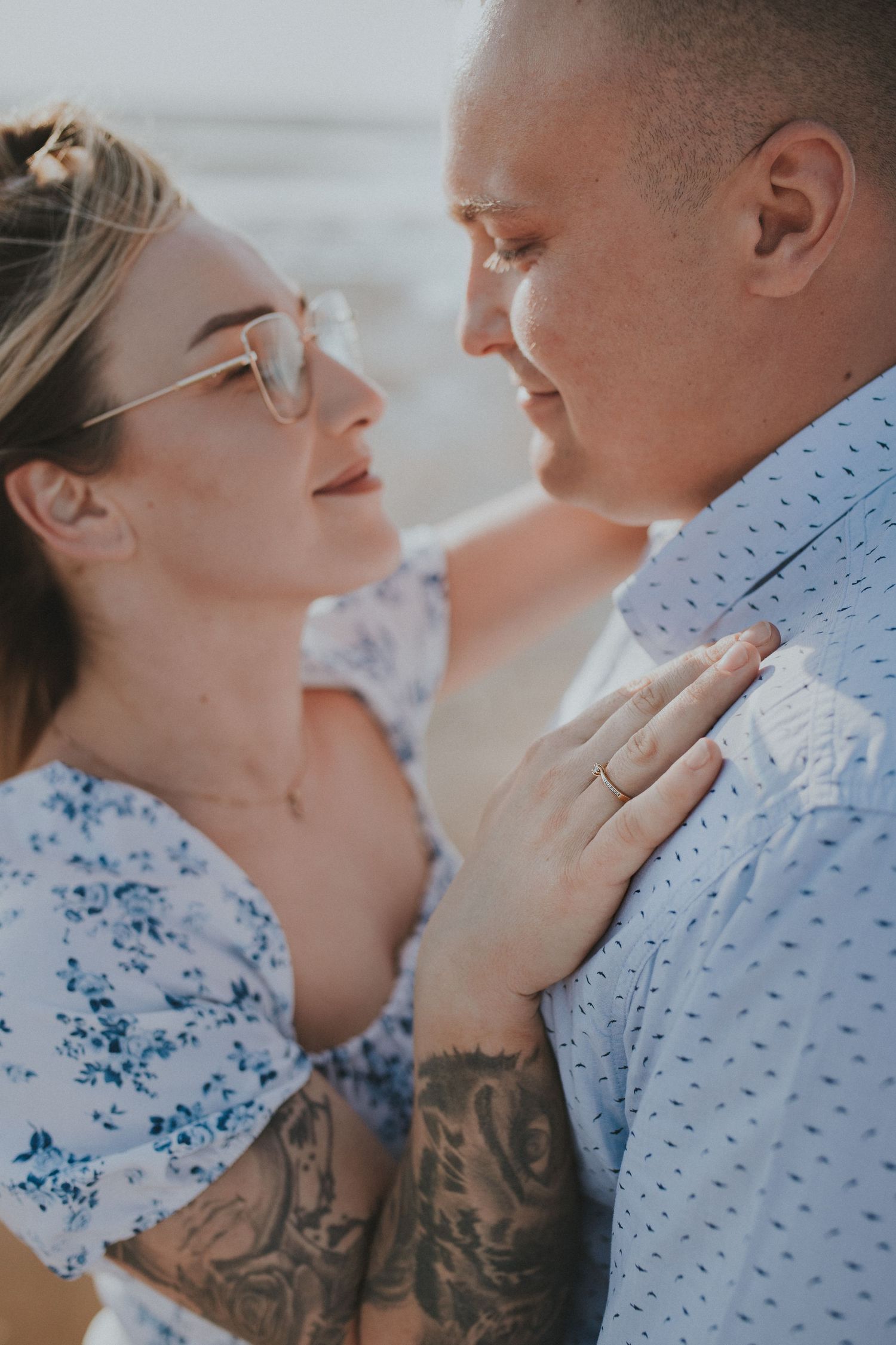 Close-up of couple sharing intimate moment against beach backdrop.