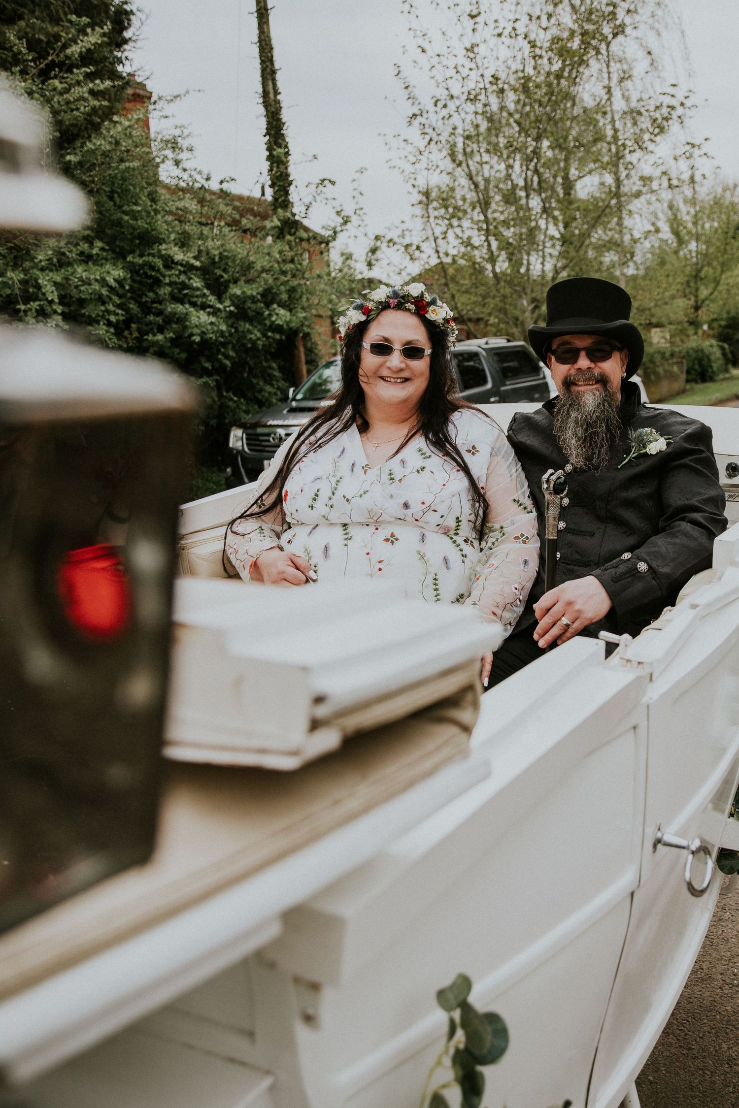 A romantic outdoor moment with a couple seated in a vintage white convertible car.