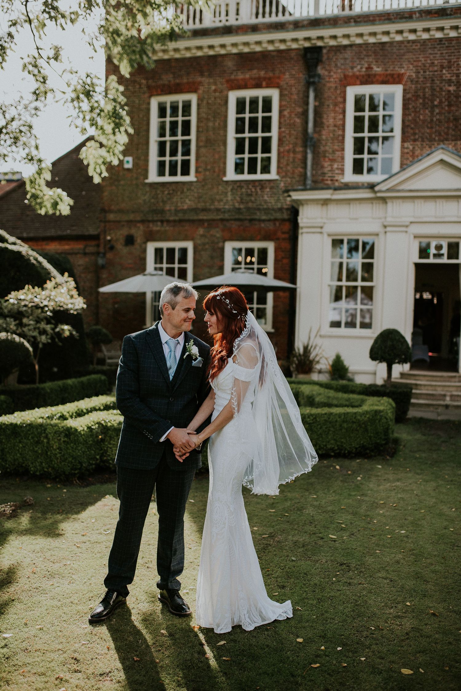 Bride and groom share intimate moments in garden of historic brick estate.