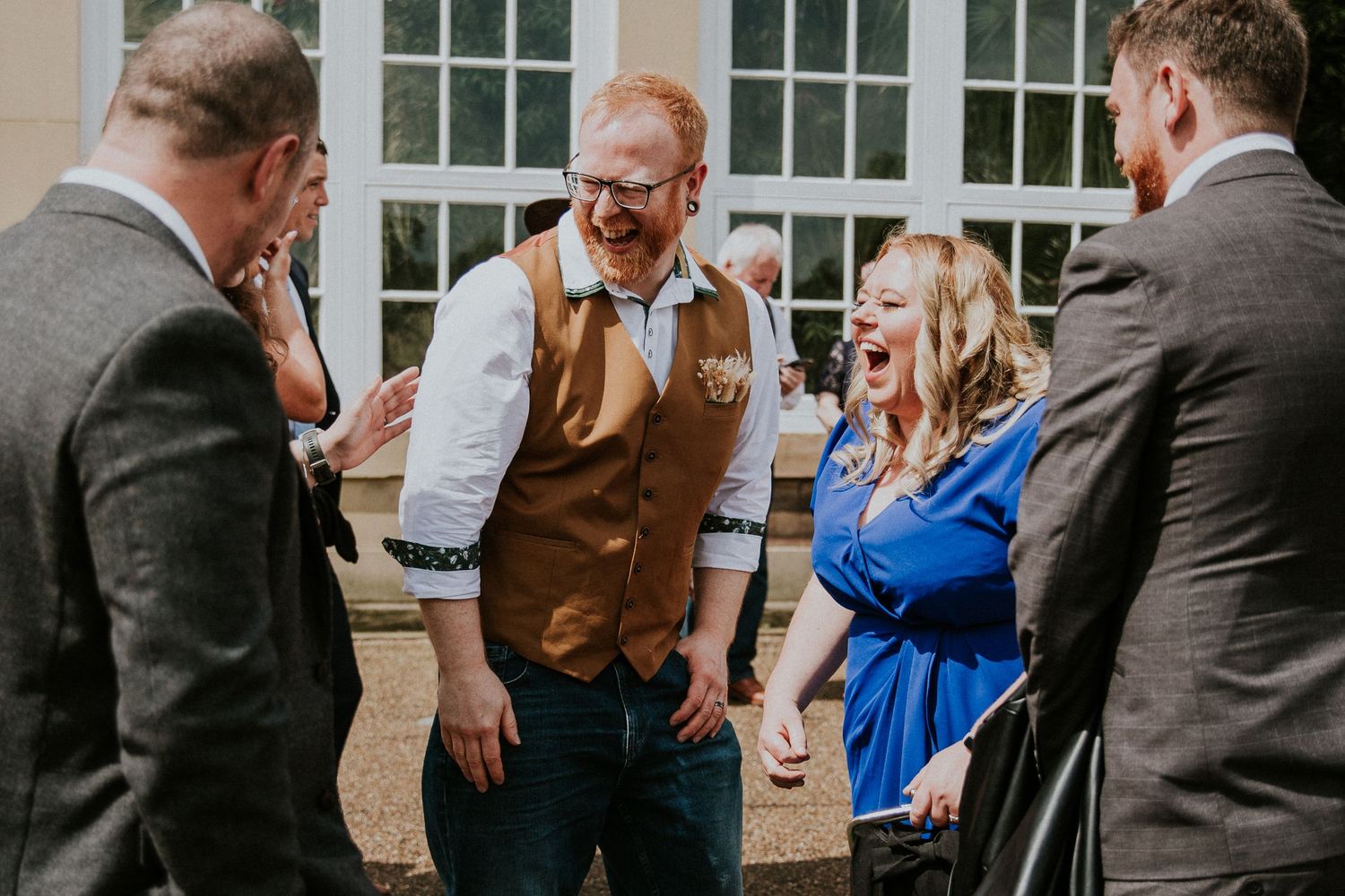 Candid moment of wedding guests laughing together outside venue.