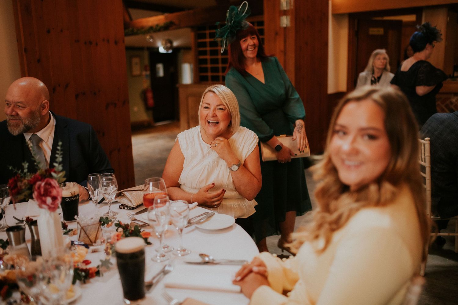 Wedding guests enjoying a reception dinner in a rustic wooden venue.