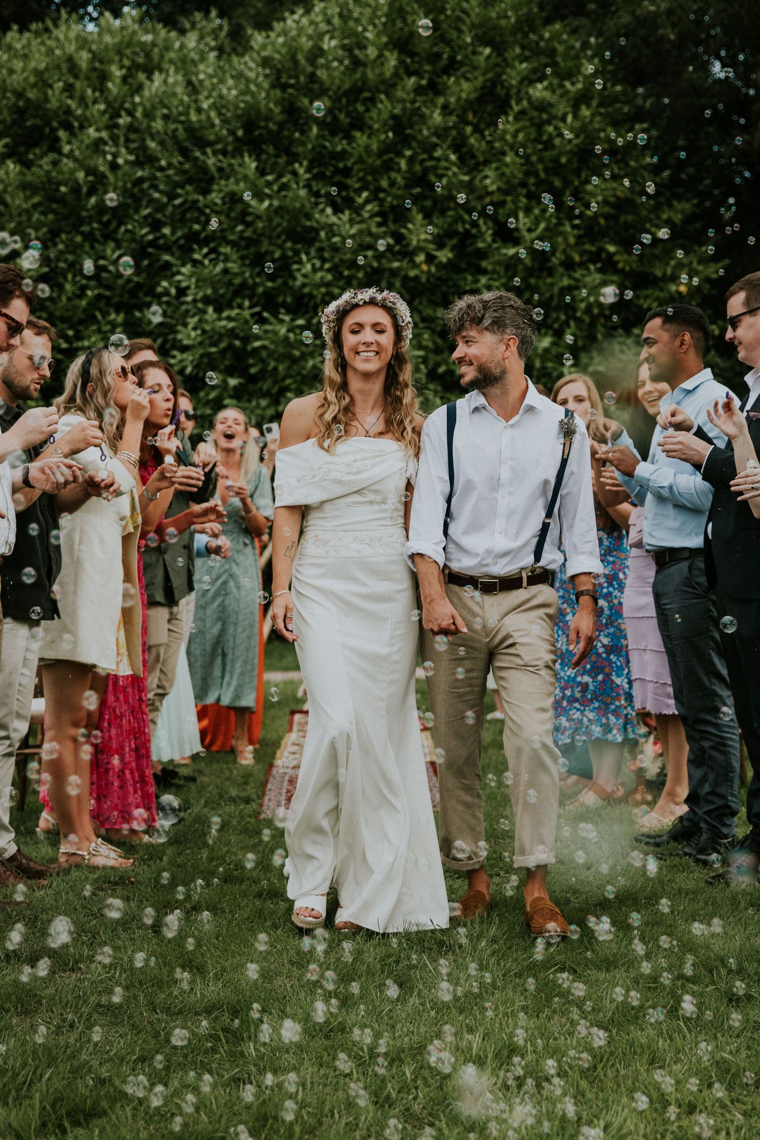 Wedding guests gathered outdoors in a meadow filled with white wildflowers.