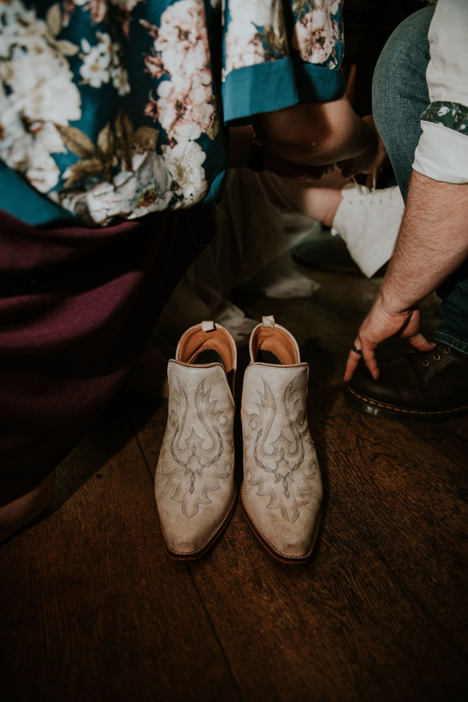 Detailed shot of embroidered western-style wedding boots on wooden flooring.