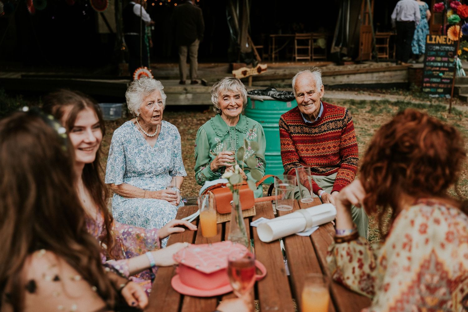 Wedding reception guests seated at decorated outdoor tables with festive decor.