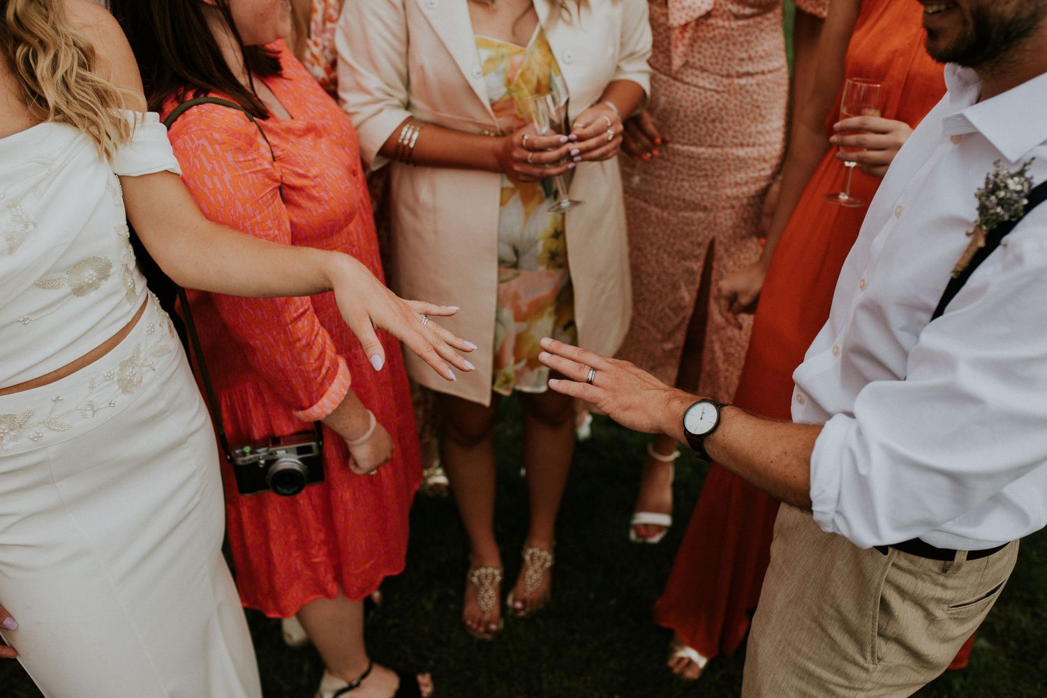 Wedding guests in bright summer attire socialize during outdoor reception.