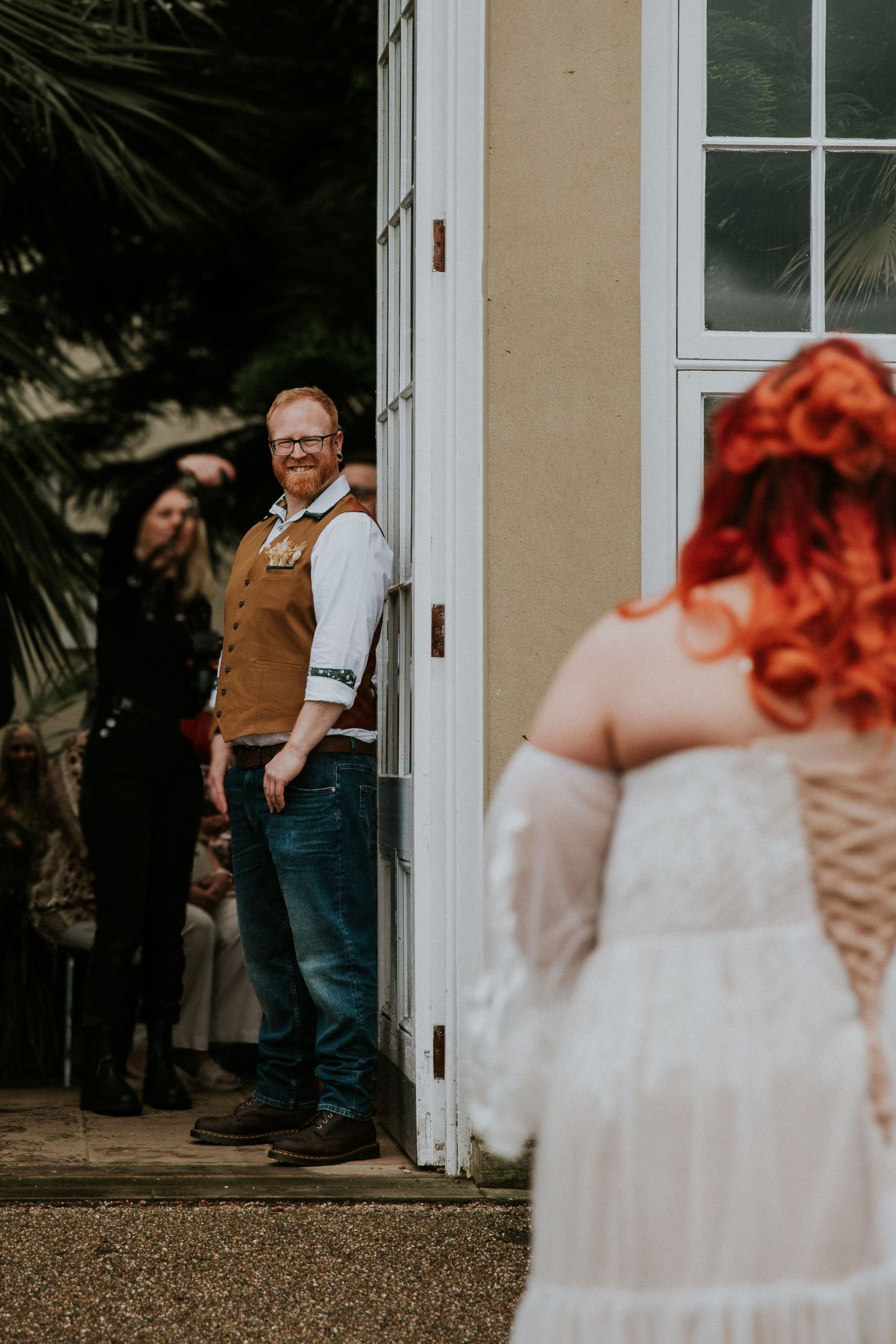 A first look moment between newlyweds at the entrance of a white building.