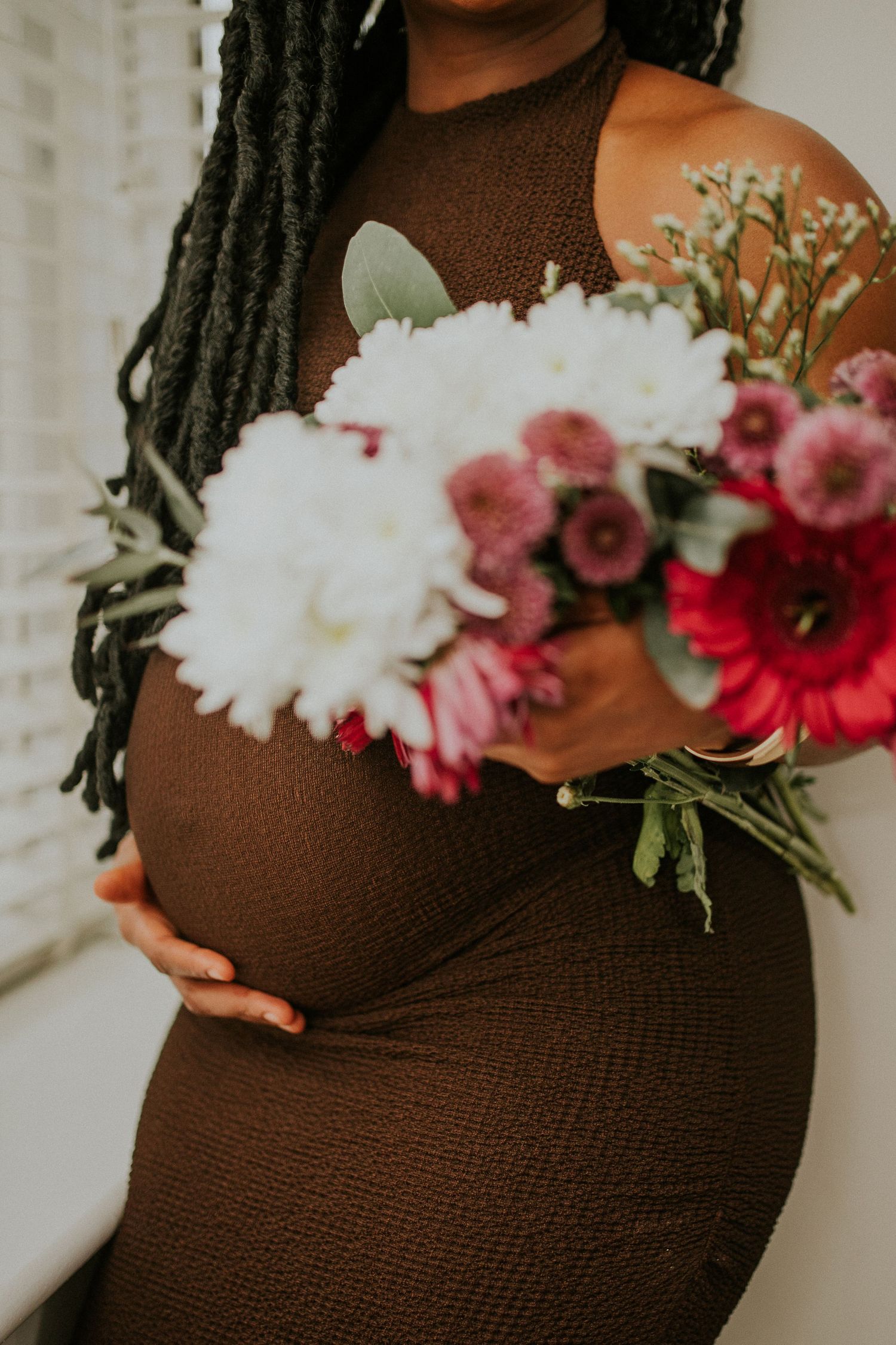 Maternity photo showing brown dress adorned with pink and white flowers.