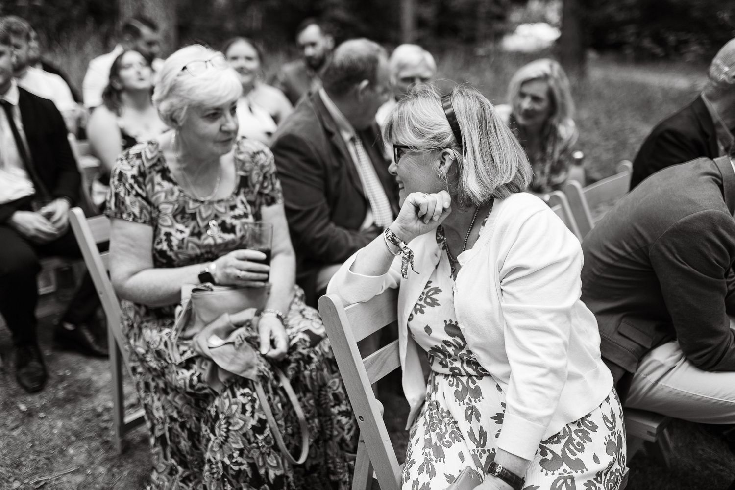 Black and white photo of wedding guests mingling during outdoor ceremony.
