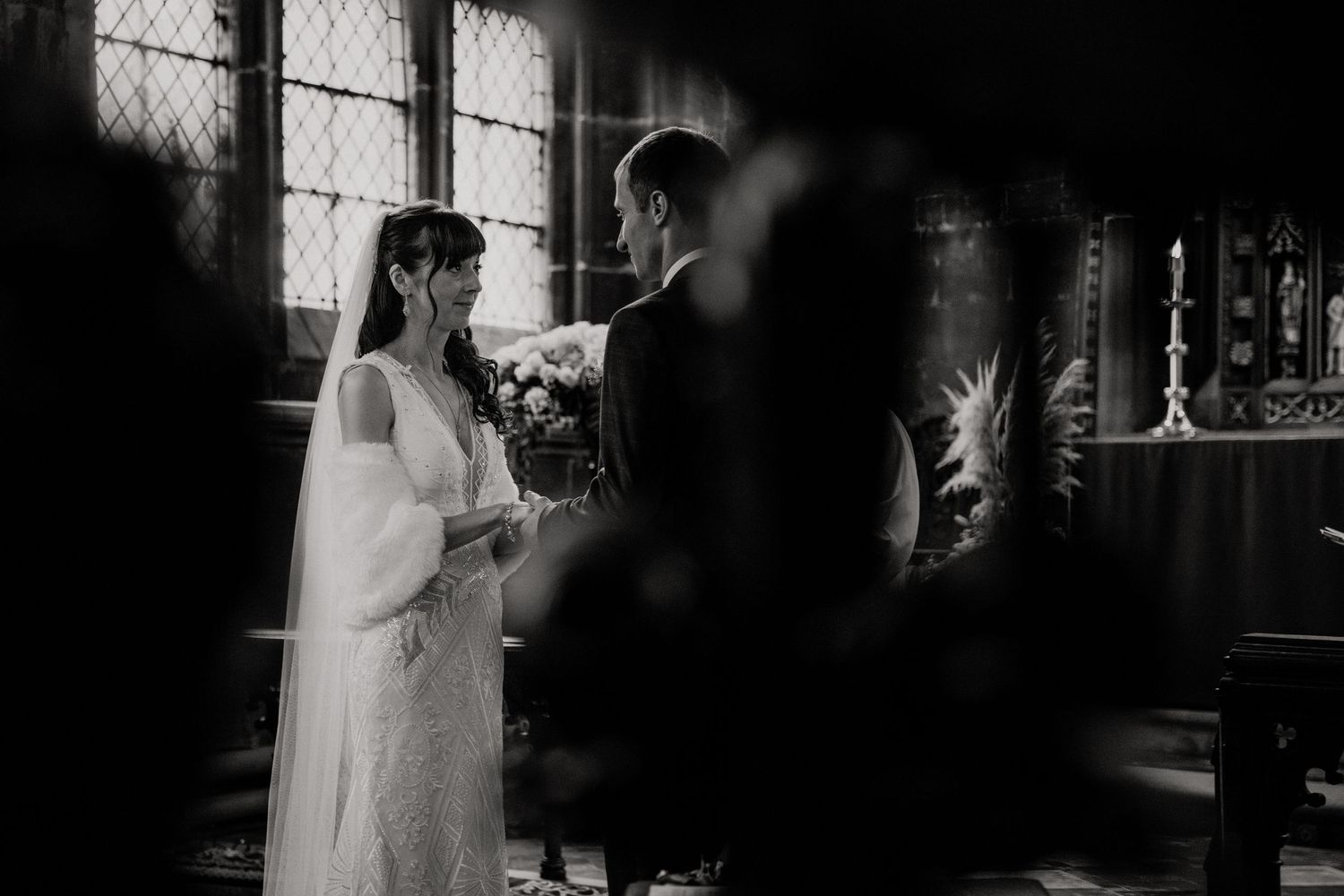 Traditional wedding ceremony taking place in dimly lit historic church interior.