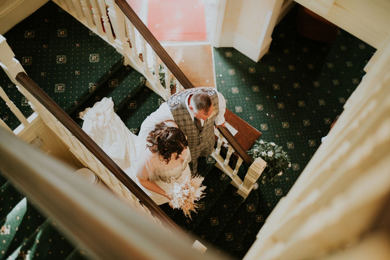 Classic wedding venue interior with white staircase and patterned carpet.