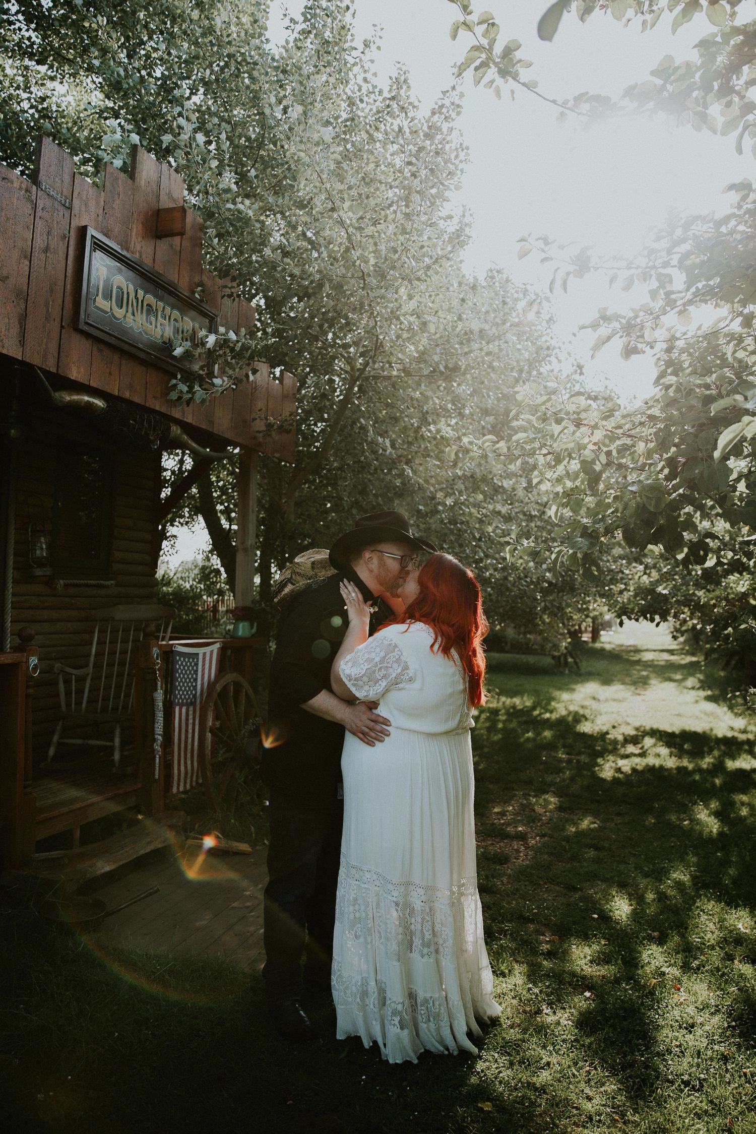 Newlyweds share romantic moment outside rustic wooden building.