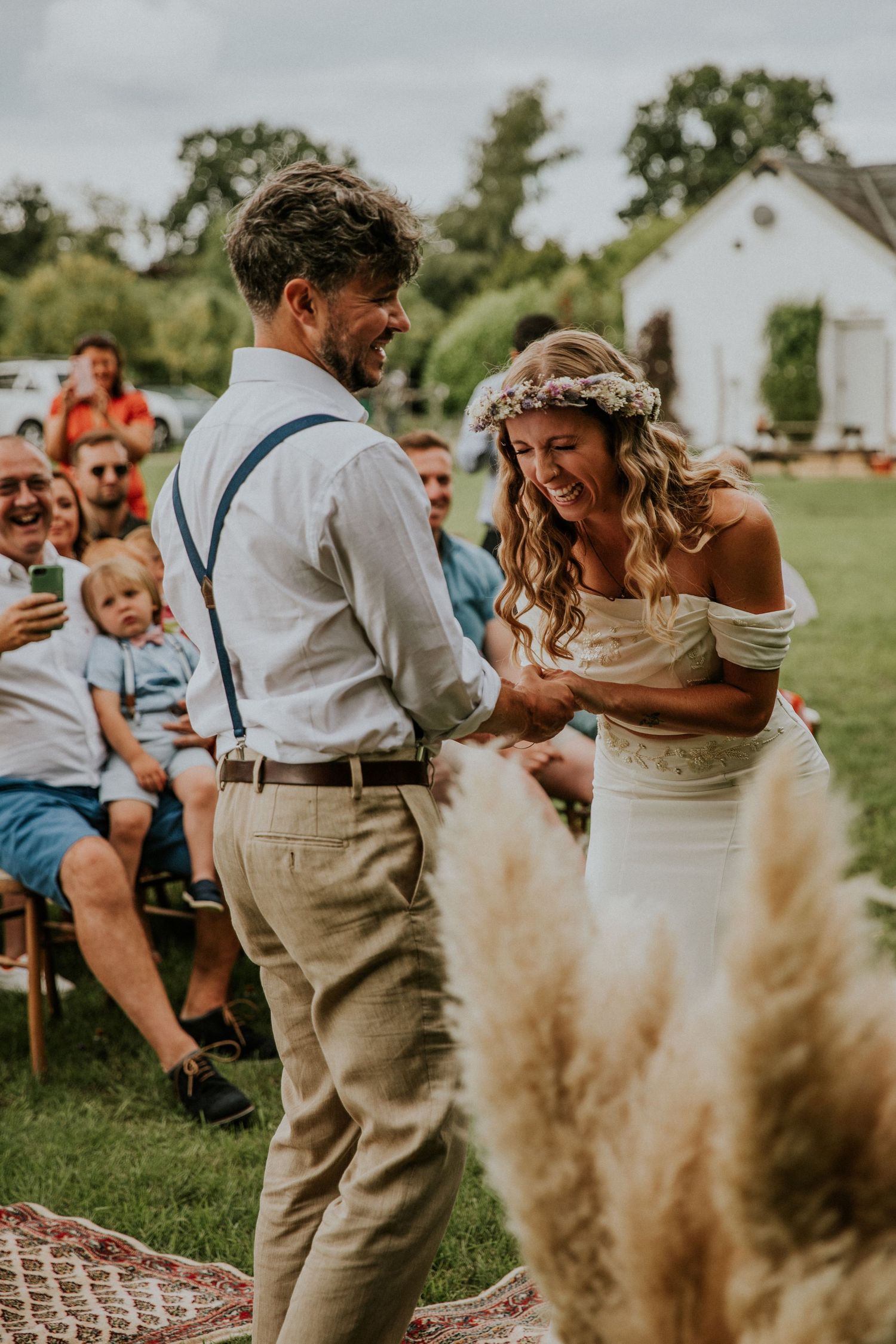 Wedding couple dancing outdoors with pampas grass decorations in the foreground.