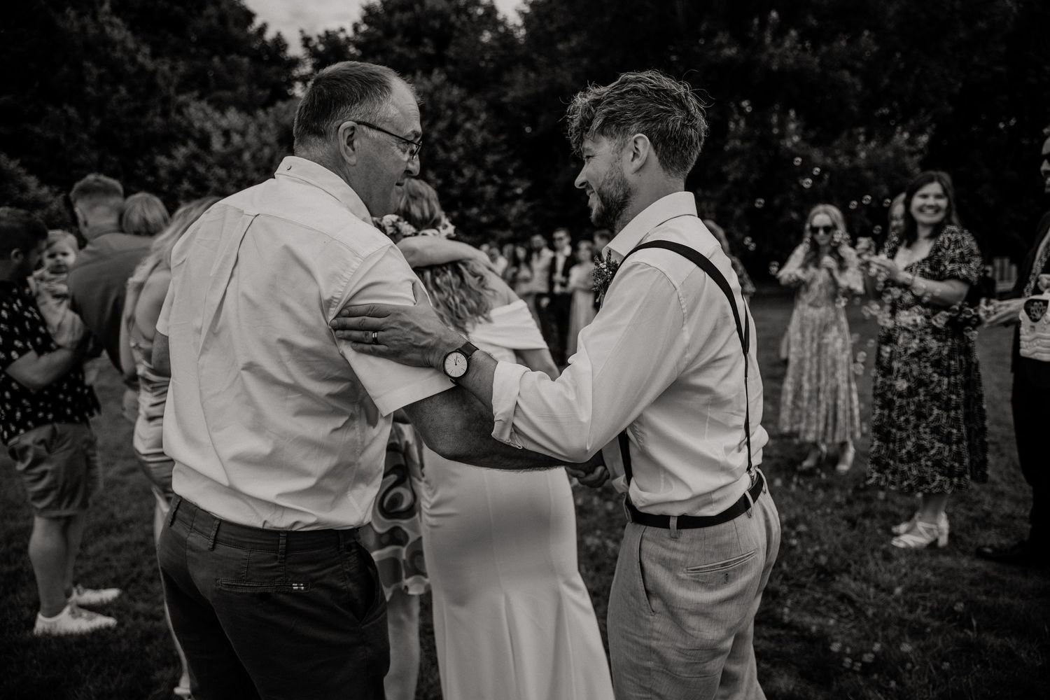 Black and white photo of emotional moment between family members at outdoor wedding ceremony.