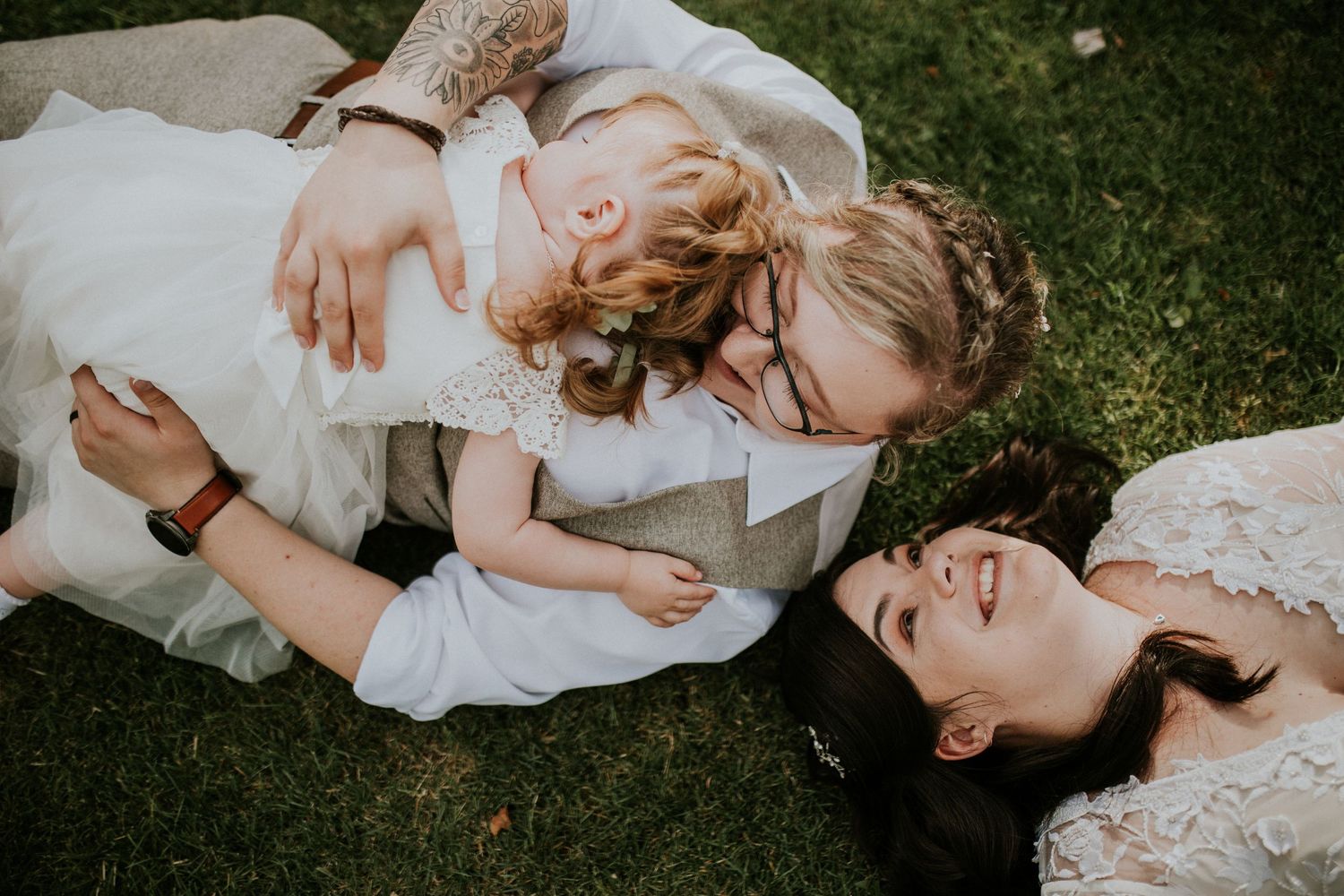 Intimate moment shared on grass during wedding celebration.