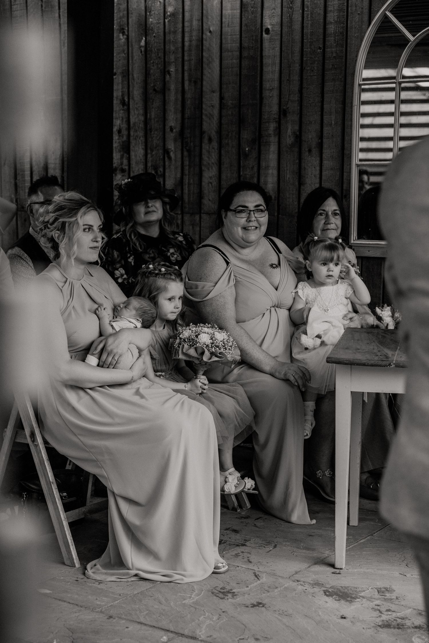 Black and white photo of wedding party seated on a covered porch with arched details.