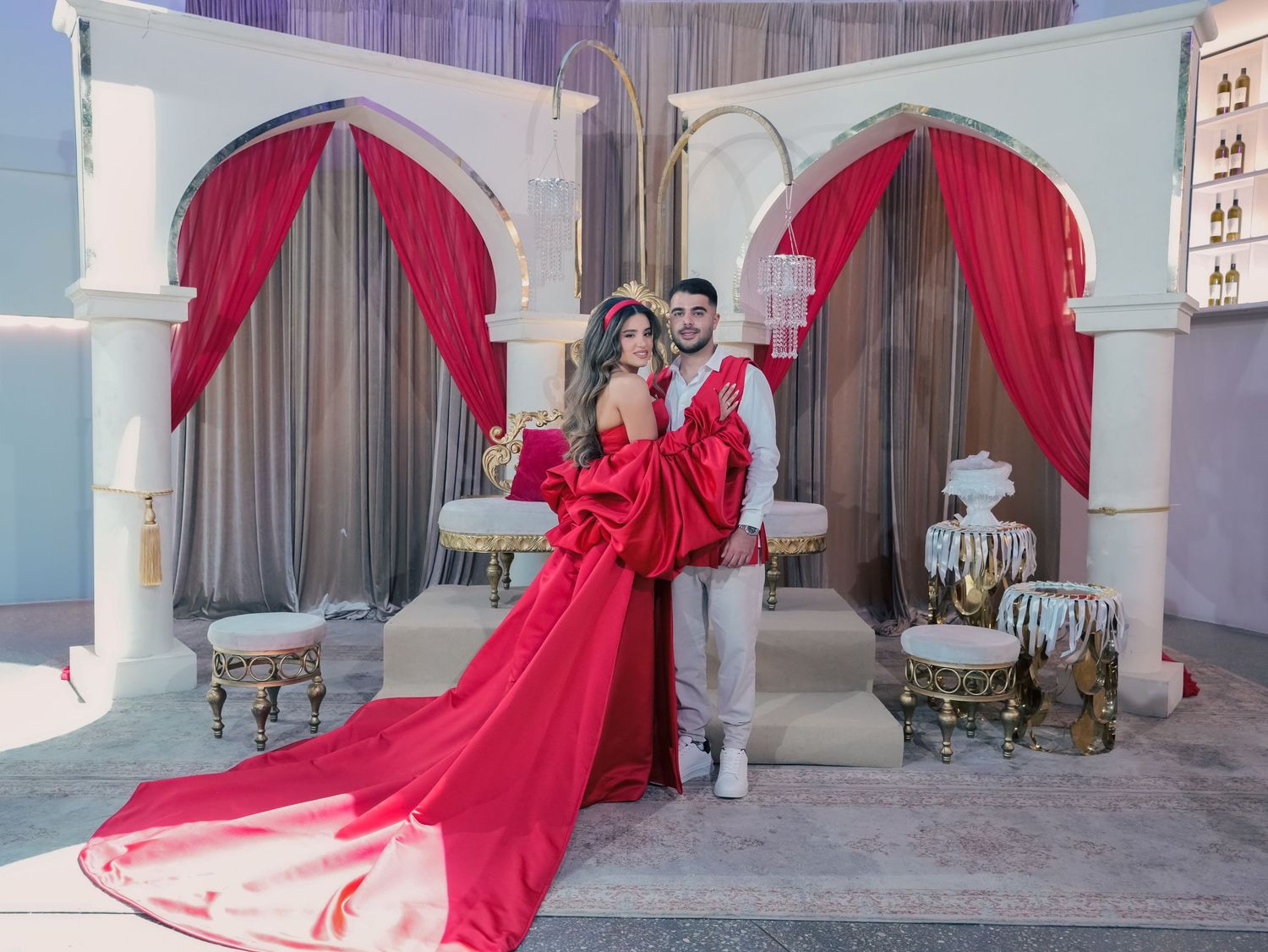 Wedding venue decorated with dramatic red fabric draping and elegant white architectural elements.