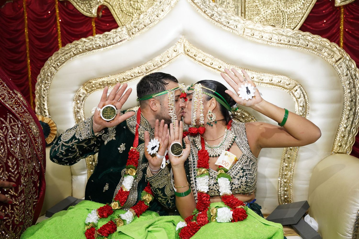 Decorative gold throne setup with red velvet curtains for wedding photography.