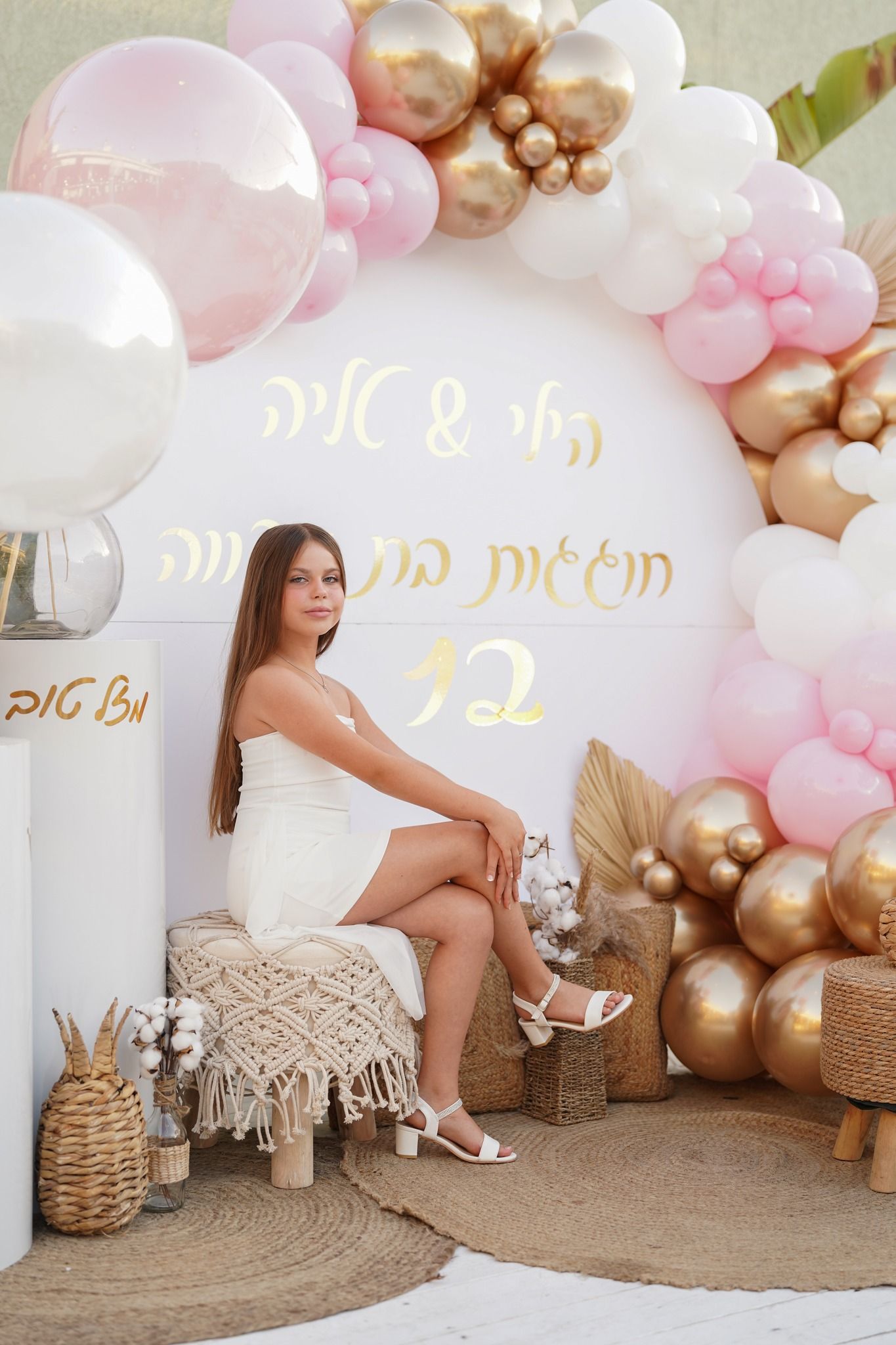 Festive balloon arch with pink and gold colors framing a decorative seating area.
