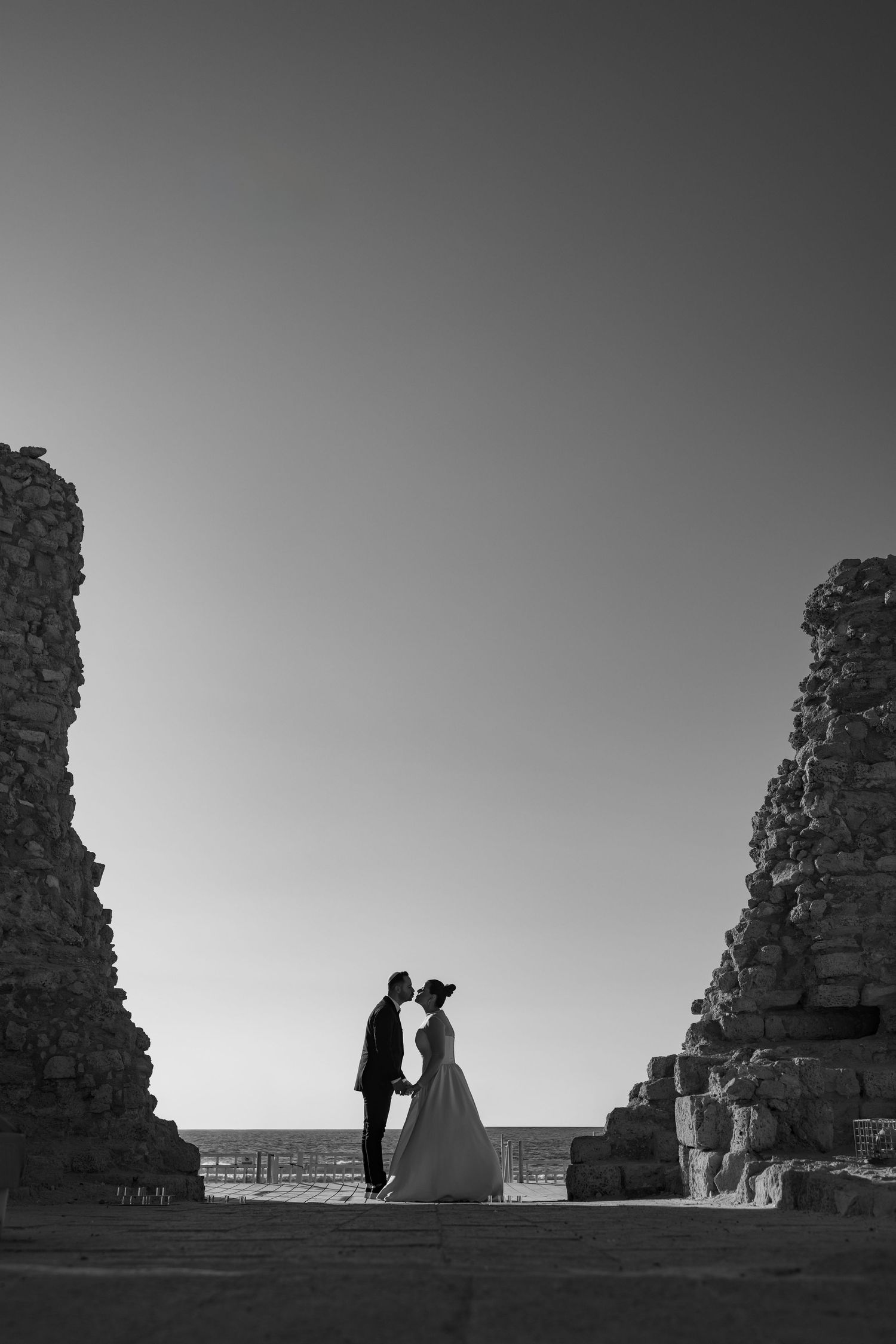 Dramatic black and white silhouette of couple among ancient stone ruins.