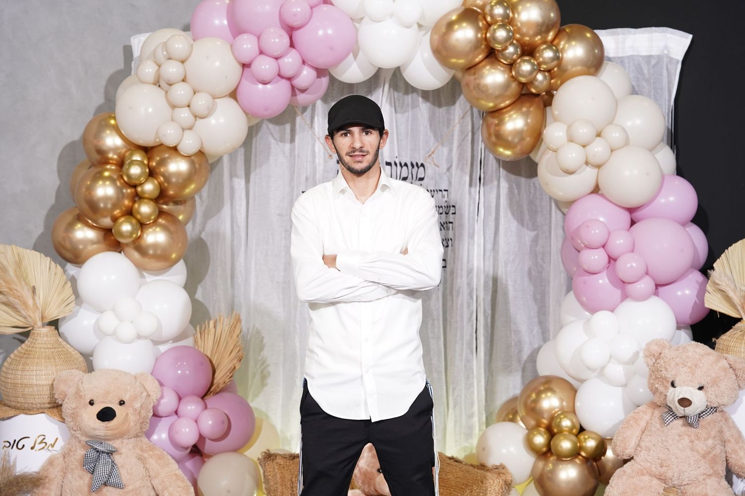 Party setup with pink and gold balloon arch and teddy bear decorations.