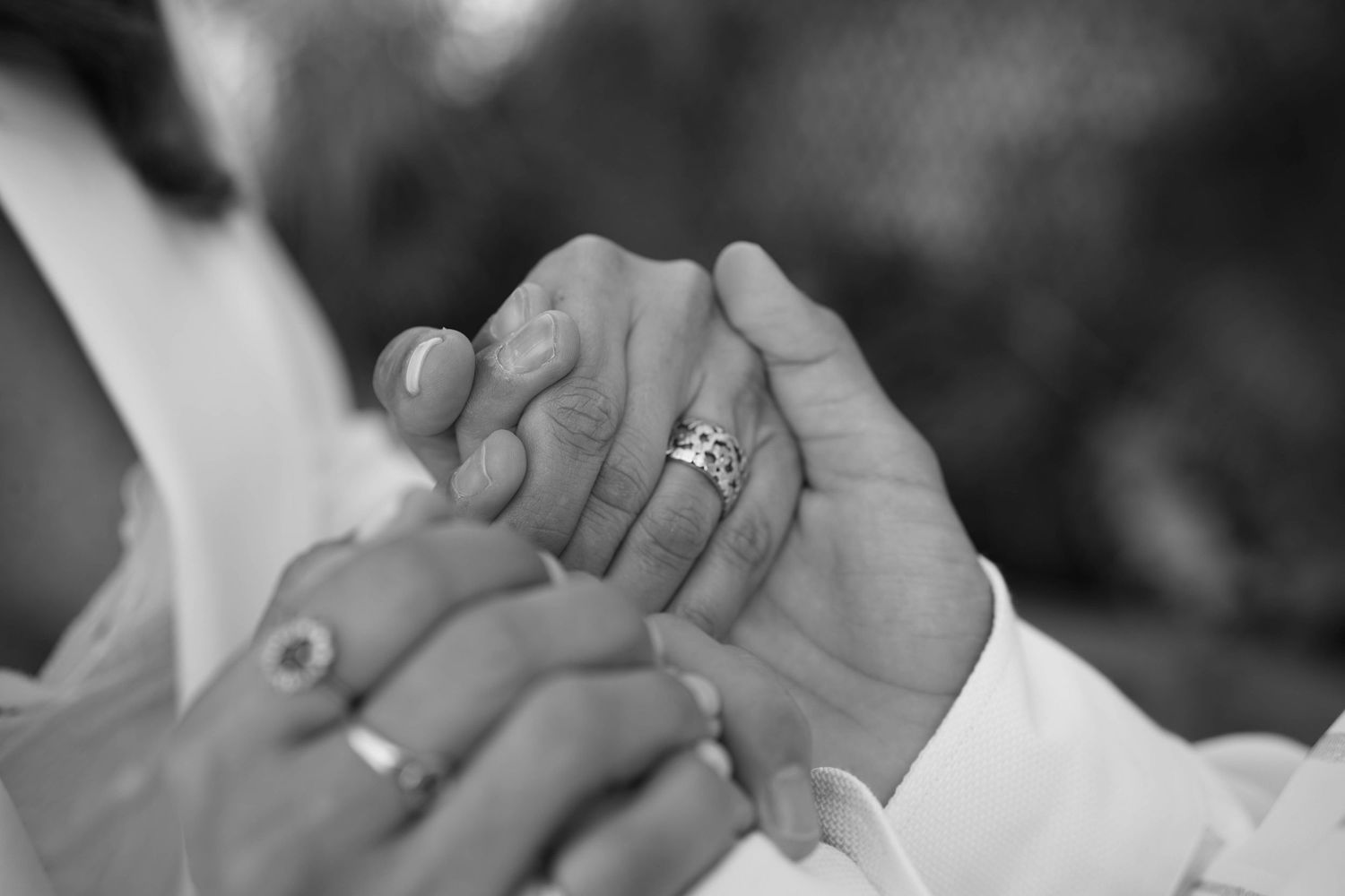Close-up black and white photo of hands with rings.