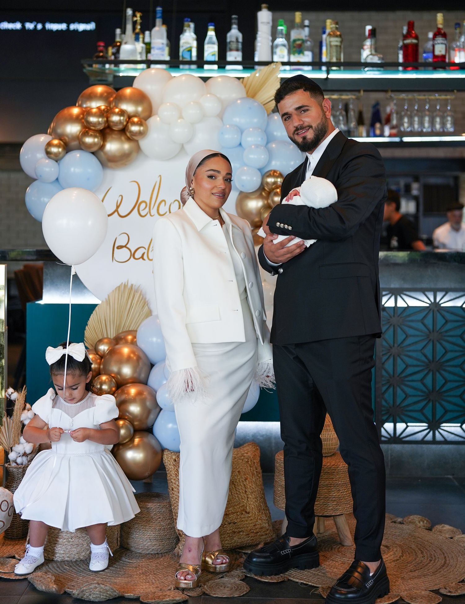 Family celebration with balloon decorations and formal attire at a bar setting.