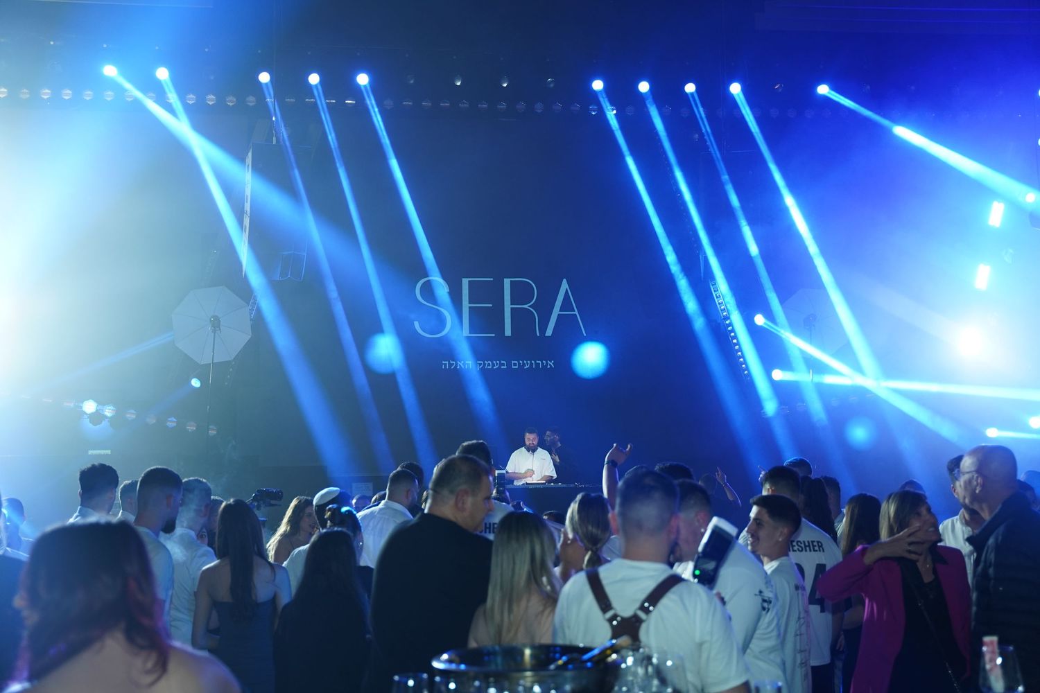 Concert venue with dramatic blue lighting and crowd silhouettes creating an atmospheric ambiance.