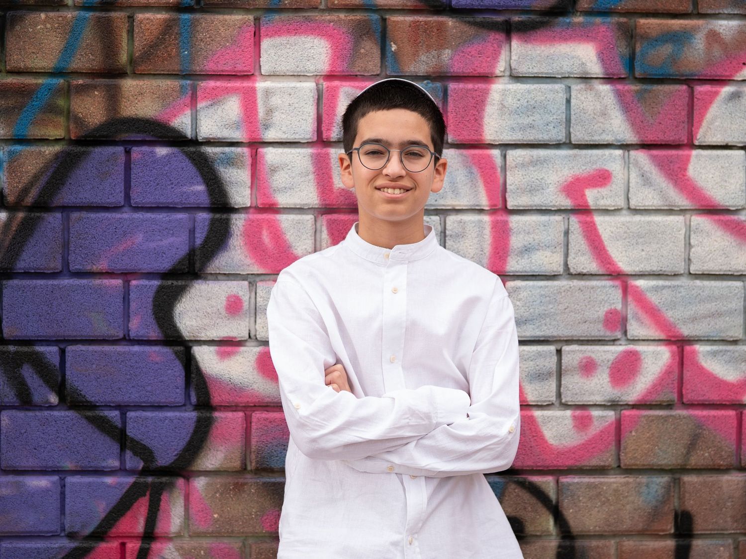 A casual pose against an urban wall with vibrant graffiti artwork.