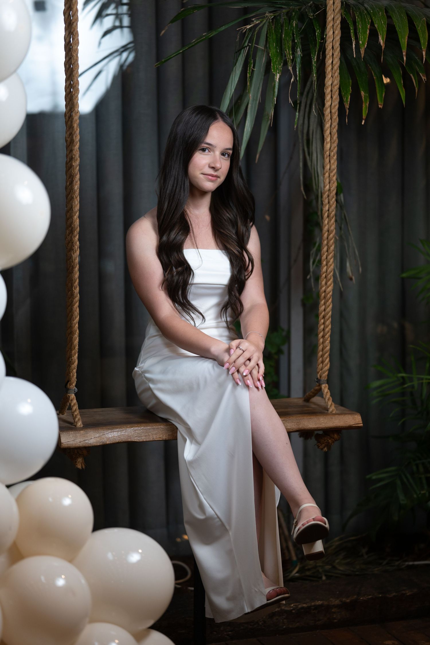 A wooden swing decorated with white balloons creates an enchanting photo setting.