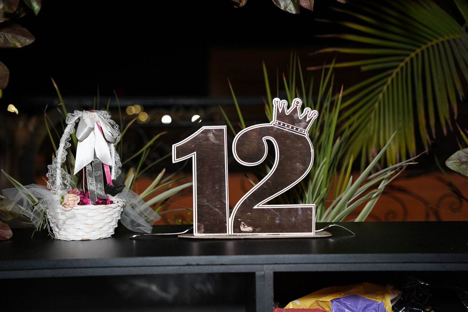 Dark evening celebration scene with illuminated number decorations and palm fronds.