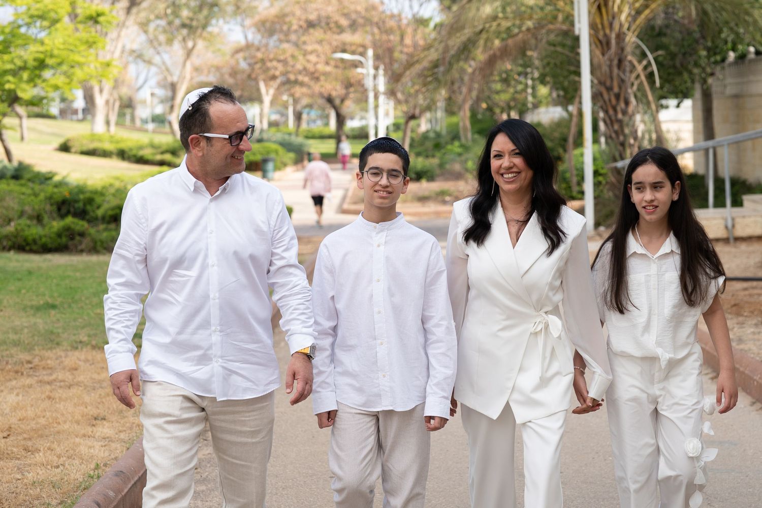 People in white outfits walking together outdoors on a sunny day.