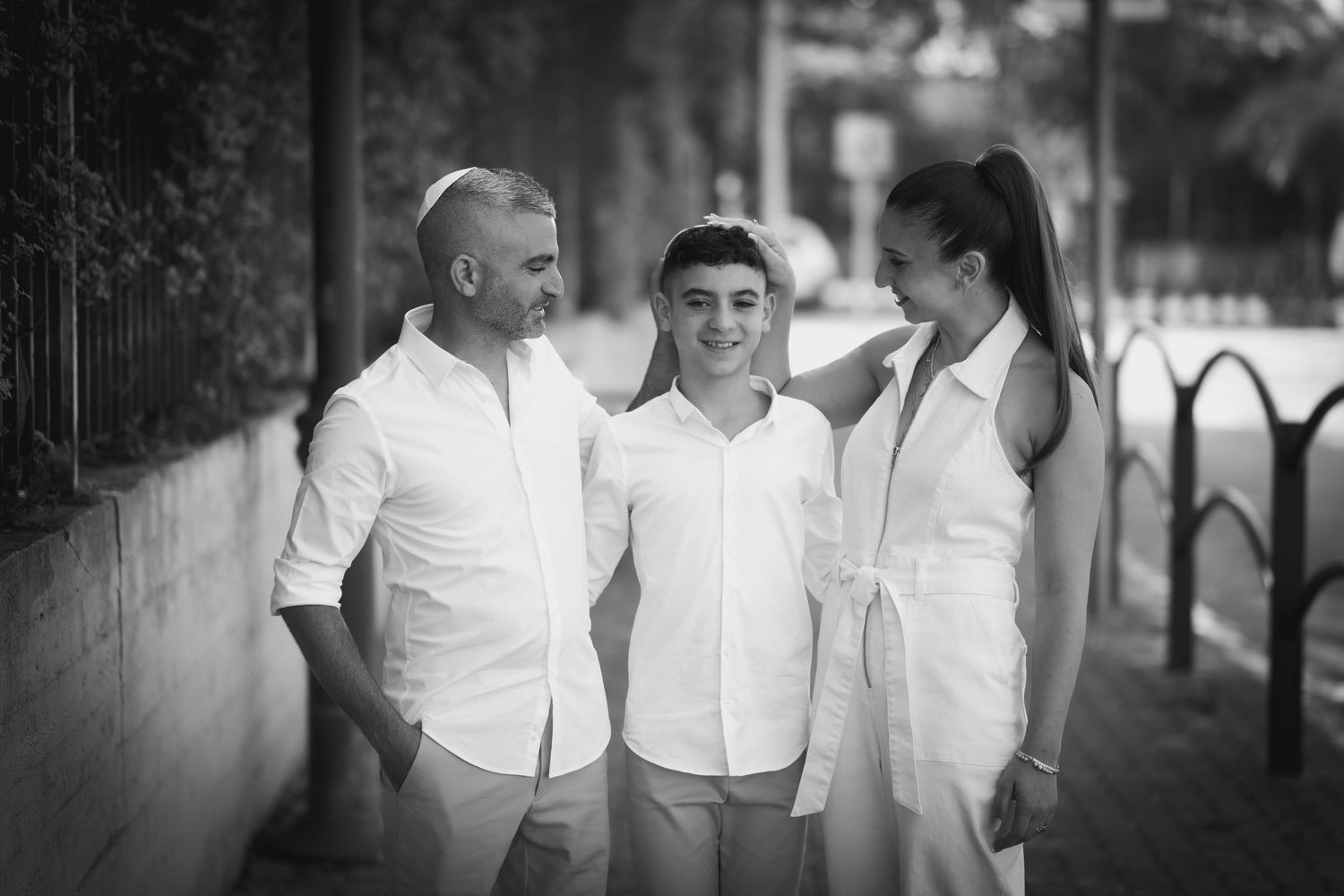 Three people in white shirts share a casual moment together outdoors.