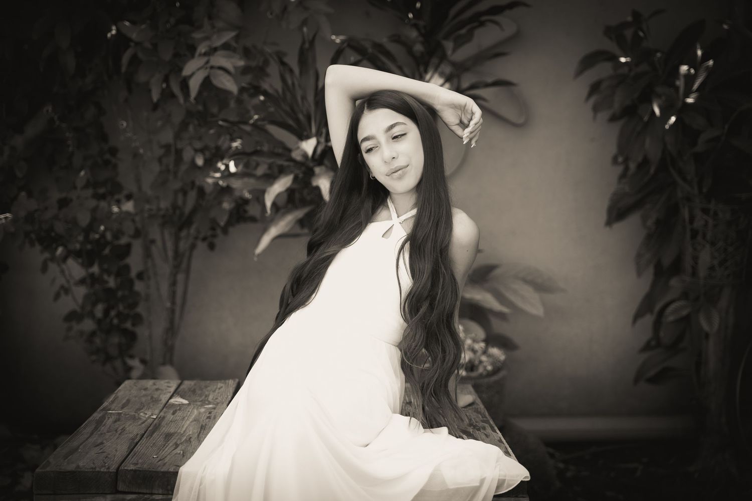 Moody black and white portrait with dramatic lighting in a garden setting.
